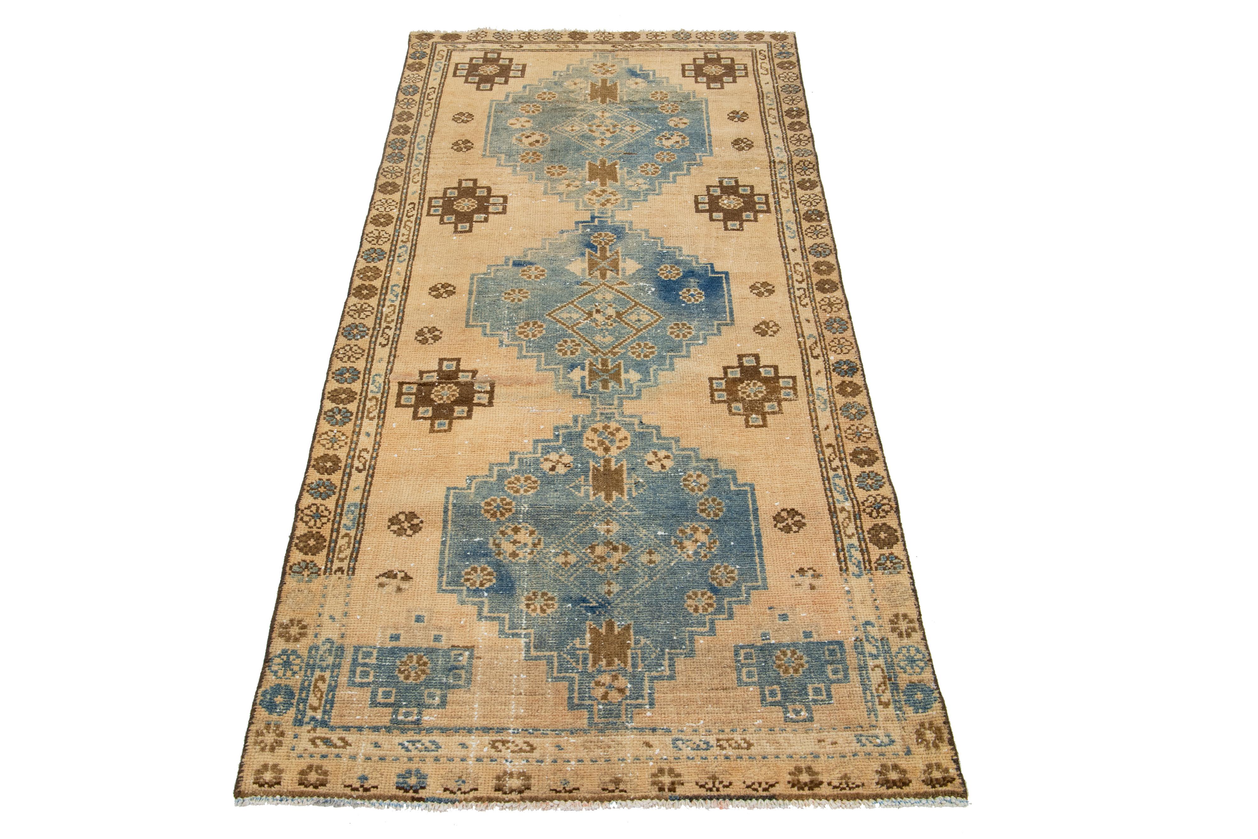 The Antique Hamadan runner is crafted from hand-knotted wool and features a tan field enhanced by a captivating tribal pattern design with blue accents.

This rug measures 3' x 6'3