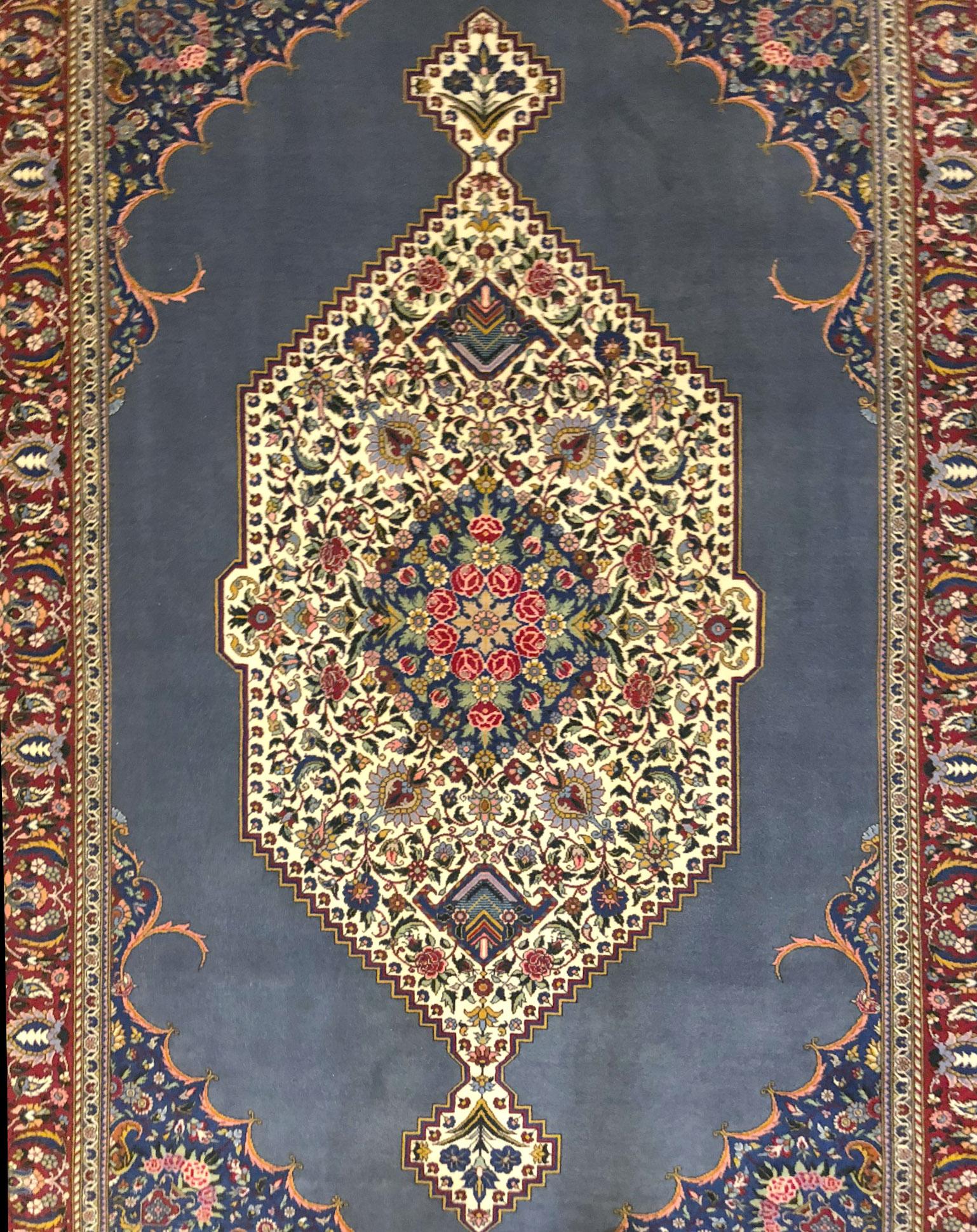 This Persian handmade rug has wool pile with cotton foundation. This beautiful rug is from Iran, Tabriz and the design is floral with open field medallion. The base color is blue and border color is dark red.