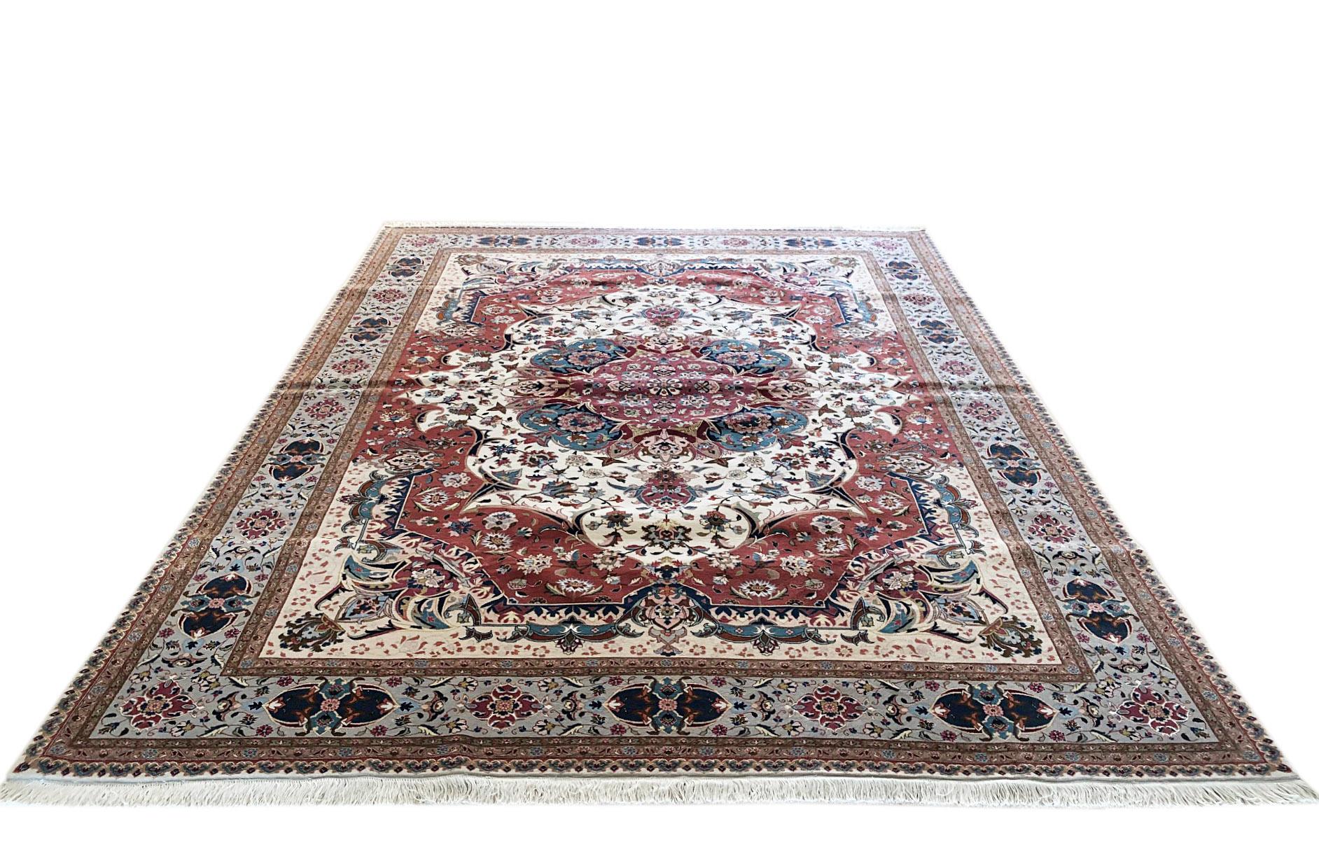 This piece is a hand knotted Persian Tabriz rug with semi-floral design (Emad Design). The pile is wool and silk with cotton foundation. The size is 8 feet 3 inches wide by feet 11 feet 5 inches tall. The base color is cream and the border is blue.