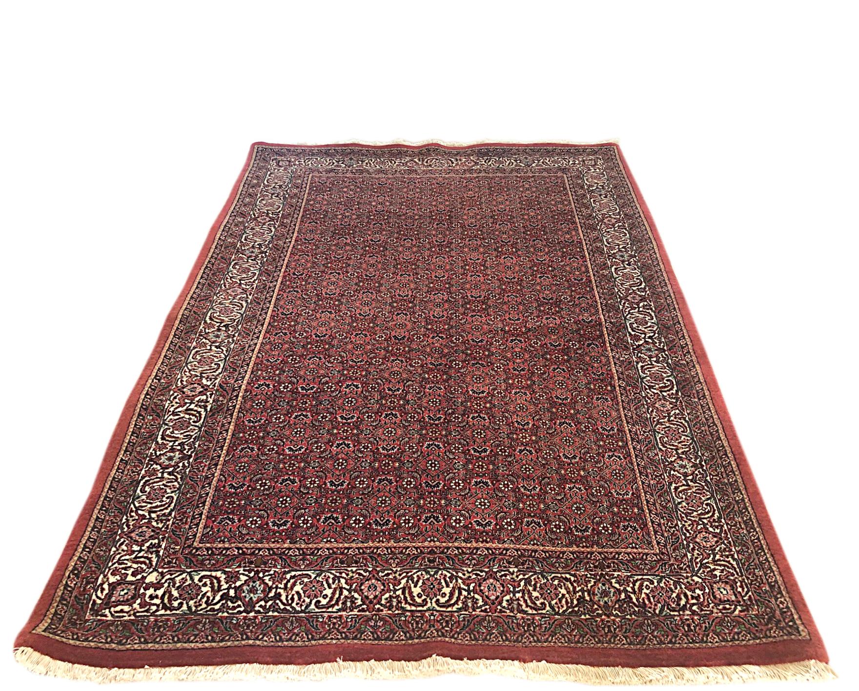 This piece is a handmade Persian Bijar rug. The pile is wool and silk with cotton foundation. The base color is red, with cream border. Bijar rugs are well-known for their craftsmanship and design. The pile is incredibly dense and strong, leading to