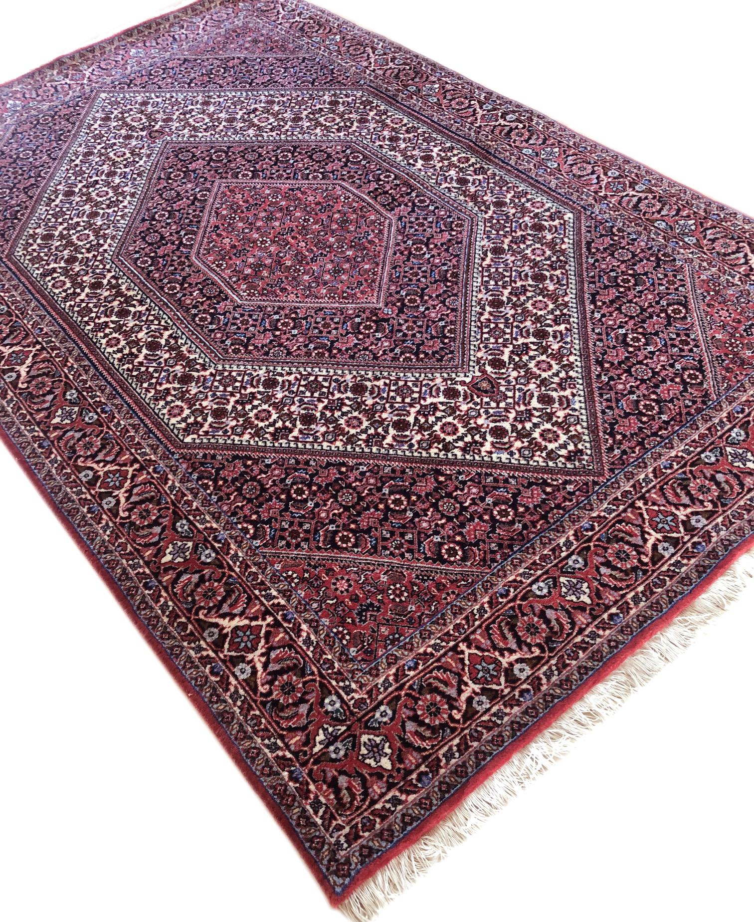 Dieses Stück ist ein handgefertigter persischer Bijar-Teppich. Der Flor besteht aus Wolle mit Baumwollbasis. Die Grundfarbe ist rot, mit schwarzem Rand. Dieser Teppich hat ein sehr detailliertes Design mit Rautenmedaillon. Bijar-Teppiche sind für