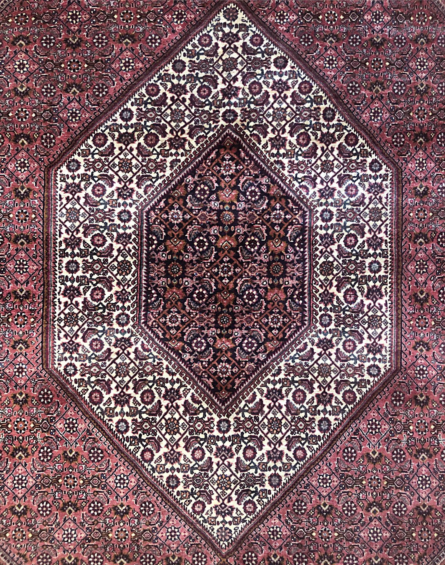 This piece is a handmade Persian Bijar rug with diamond medallion. This piece has wool with cotton foundation. The base color is red and cream, with cream border. Bijar rugs are well-known for their craftsmanship and design. The heavy wool