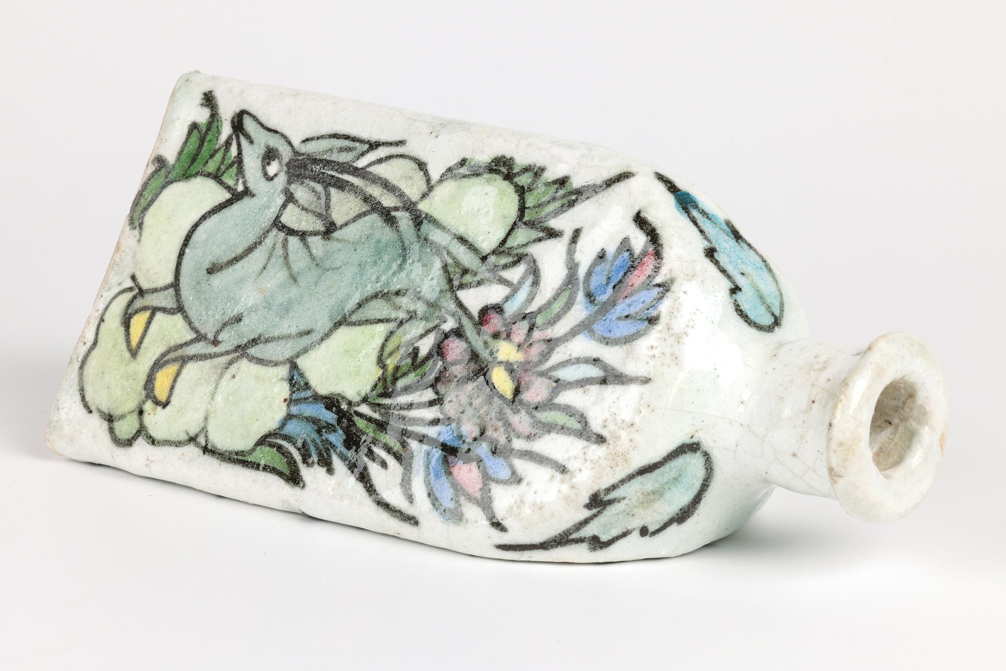 De una pequeña colección de cinco jarrones persas de cerámica pintados a mano procede este elegante jarrón de barro de forma triangular pintado a mano con ciervos entre rocas y flores y datado entre principios y mediados del siglo XX. El jarrón de