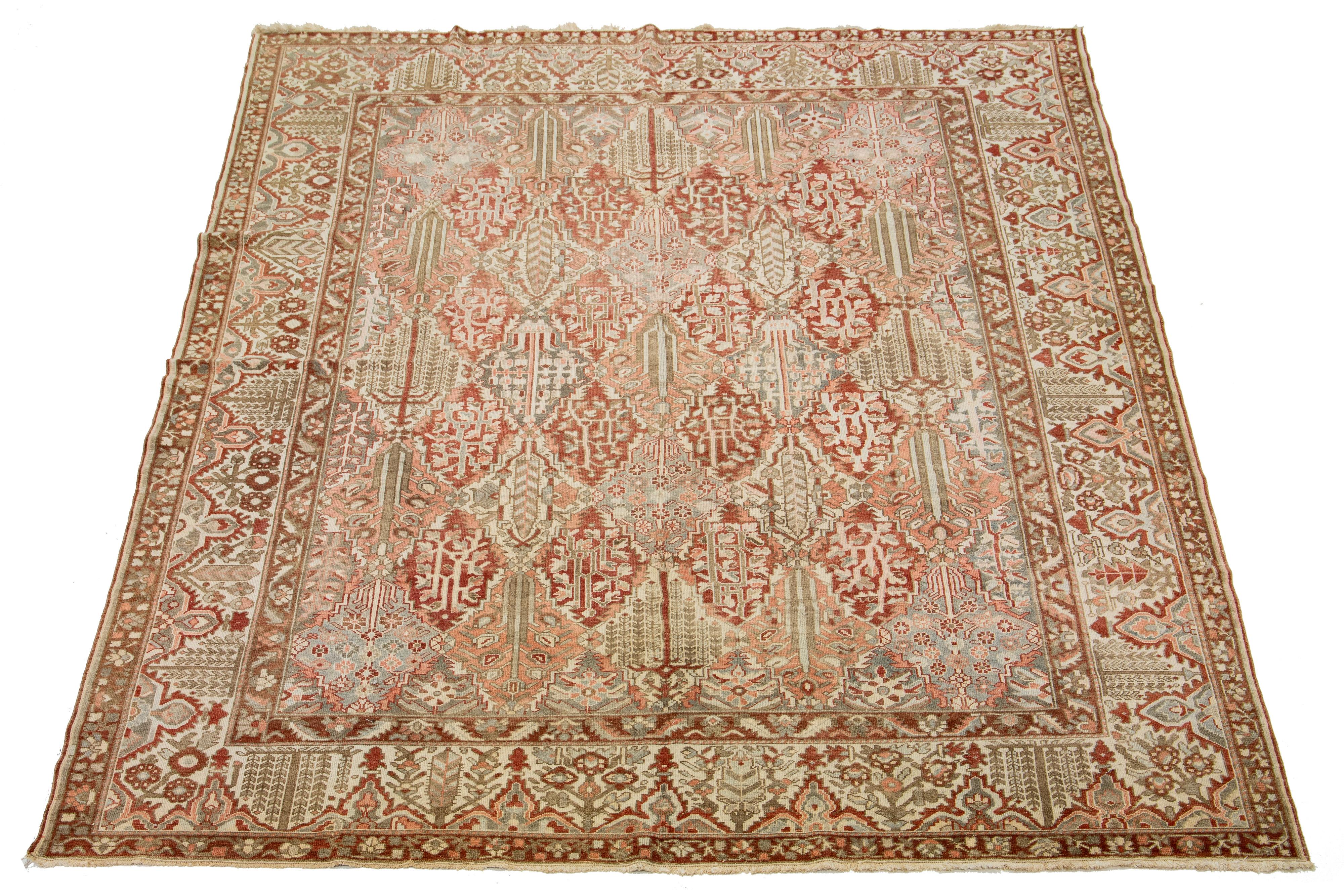 Dieser schöne antike Bachtiari-Teppich aus handgeknüpfter Wolle weist ein rostrotes Farbfeld auf. Es zeigt ein klassisches persisches Design mit blauen, beigen und pfirsichfarbenen Blumen.

Dieser Teppich misst 10'8