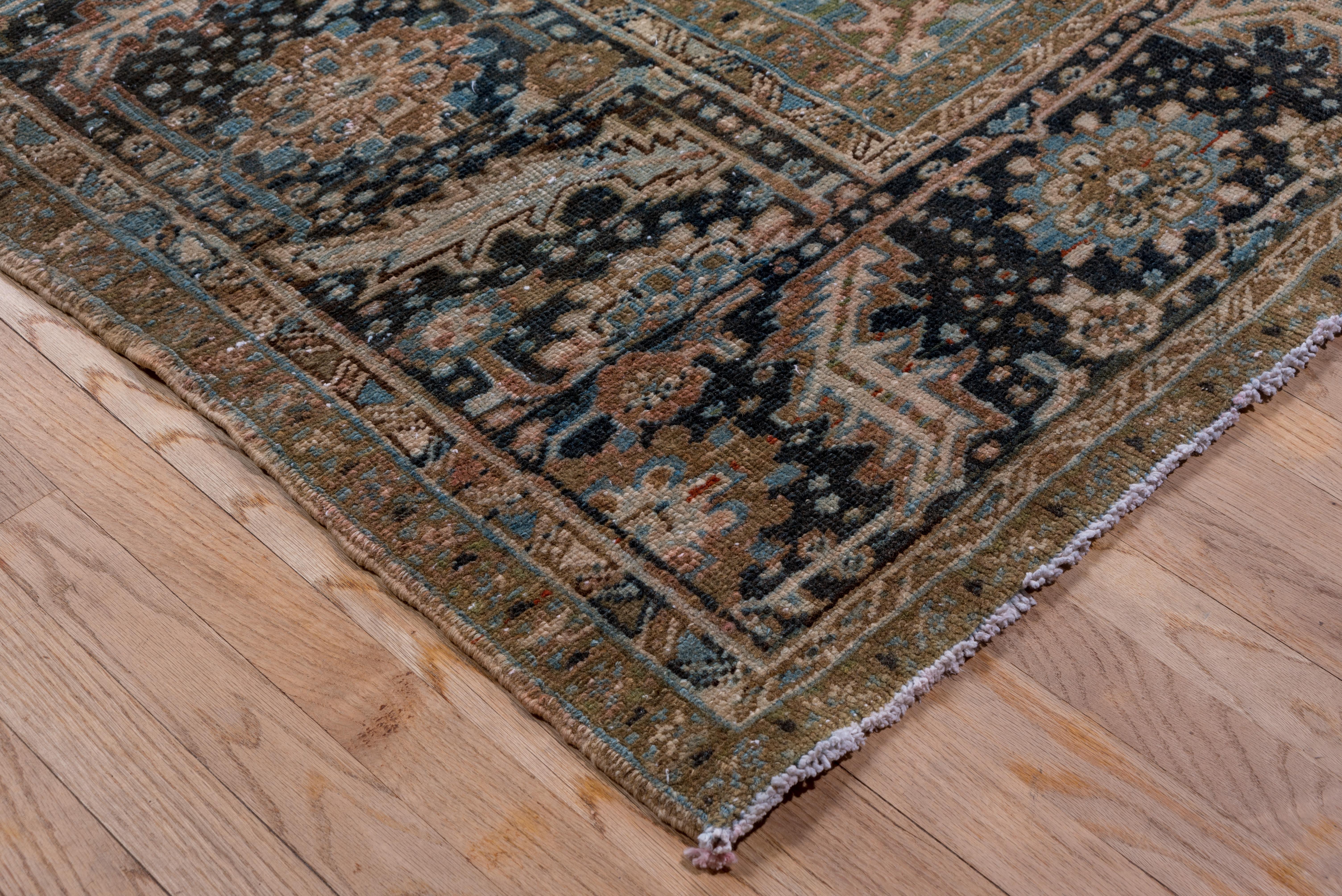 This NW Persian rustic carpet shows a rare gently scalloped round navy medallion enclosing overlapping long leaves and palmettes around an ecru octofoil centre. Soft rose field, ivory and arabesque corners, and a navy bent leaf, rosette and dot