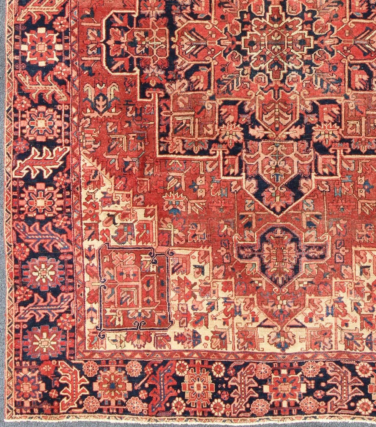 Persian Heriz Rug with Stylized Geometric Medallion in Rust and Blue. Keivan Woven Arts; rug H-1006-14, country of origin / type: Iran / Heriz, circa 1950.
Measures: 9'7 x 12'7. 
This Persian Heriz carpet from the mid-20th century bears an exquisite