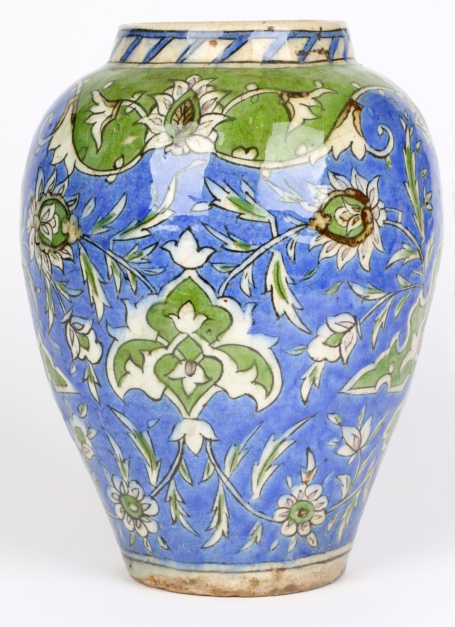 Large Persian Islamic styled hand painted floral pottery vase dating from the 19th century. The large earthenware vase is of rounded bulbous shape standing on a narrow unglazed foot rim. The body is hand painted in tones of blue, green and brown