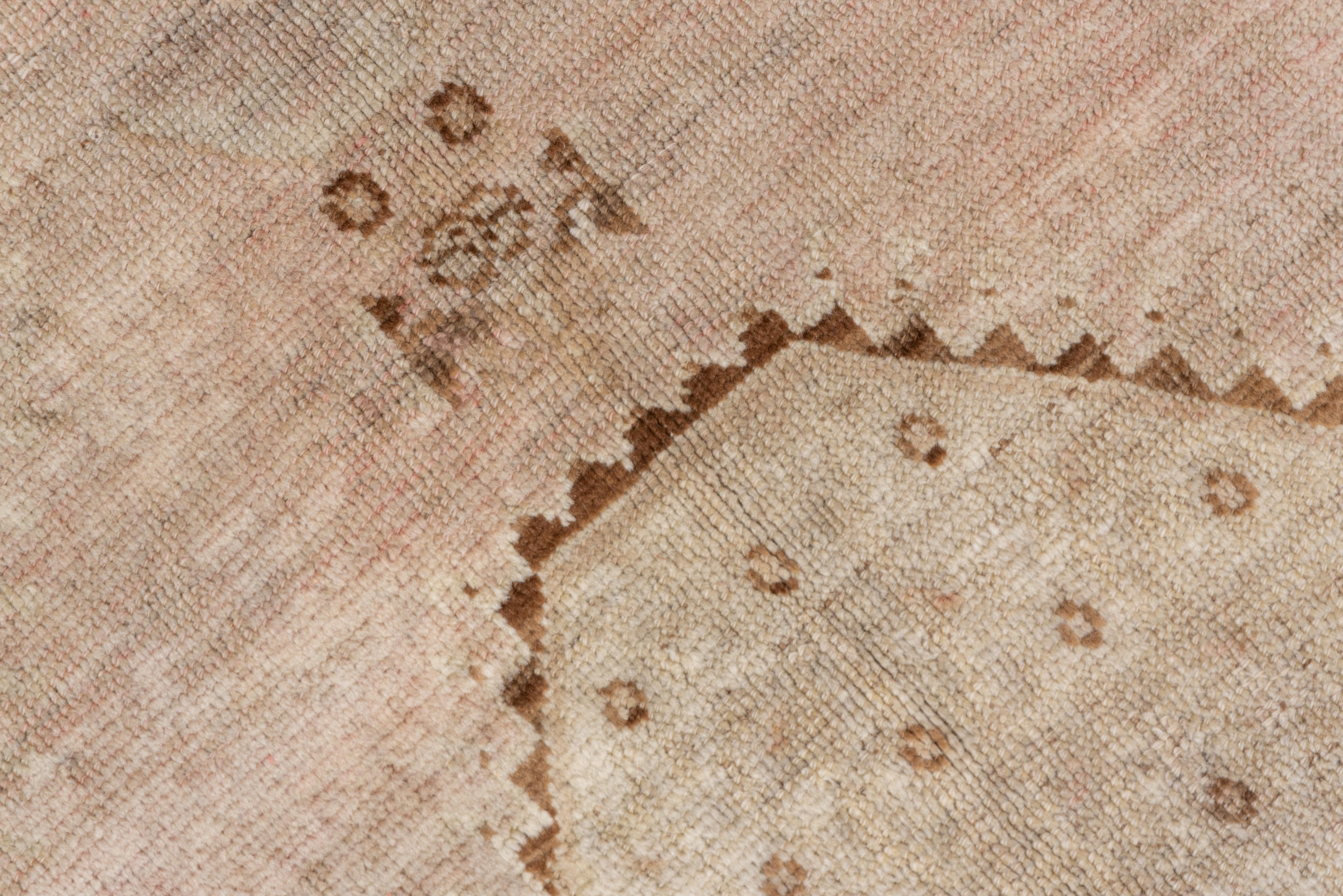 The shaped, rust central cartouche shows a Herati pattern and is set on a layered field in shades of cream and pearl. The border jogs at one end while displayed a black and brick reversing turtle palmette pattern on a putty ground.