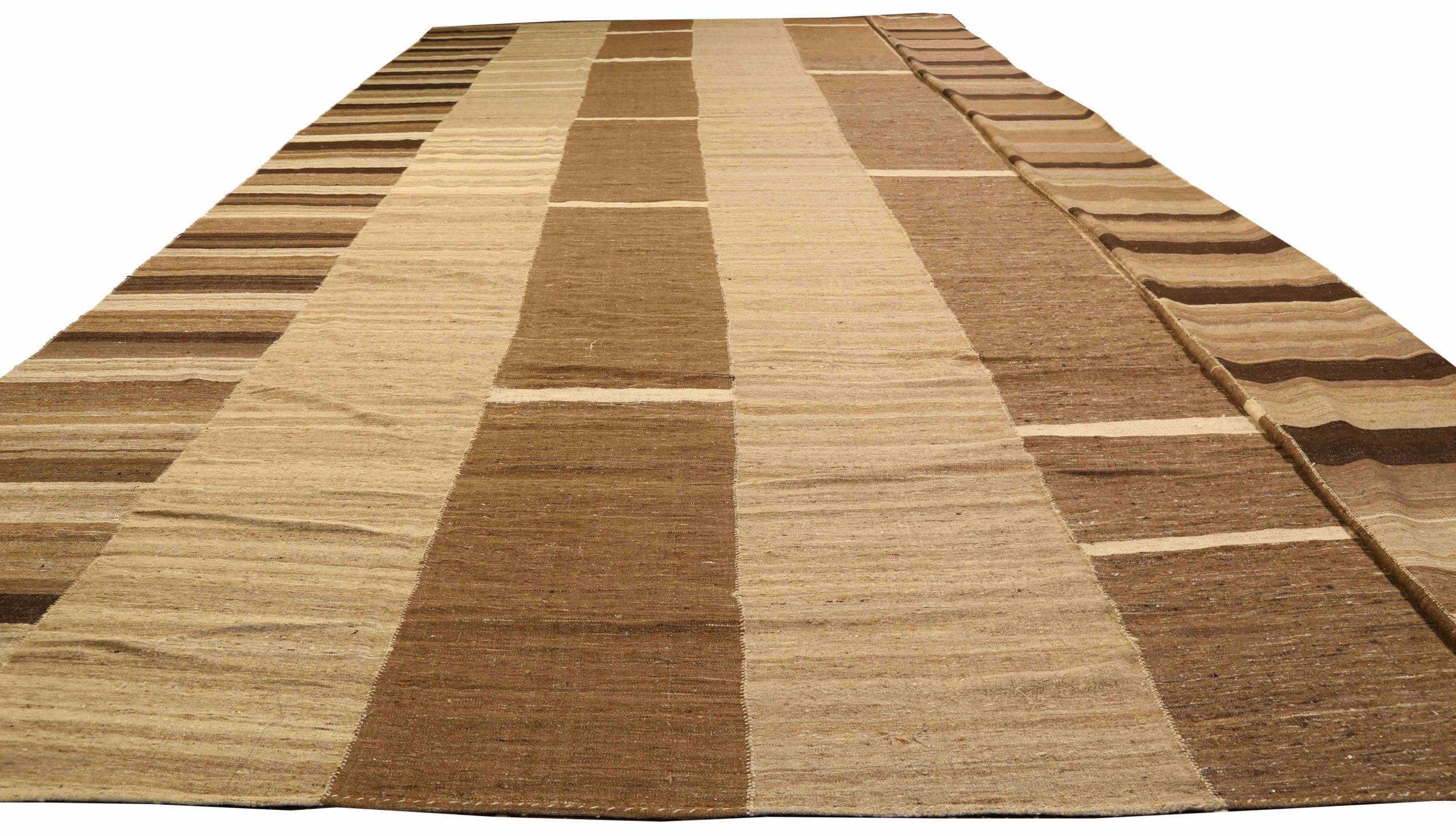 Entdecken Sie die Eleganz eines persischen Kilims mit einem übergroßen Teppich von CIRCA 1910. Dieses exklusive Design aus Wolle und Braun-Elfenbein-Taupe ist perfekt, um Ihren Raum zu verschönern.