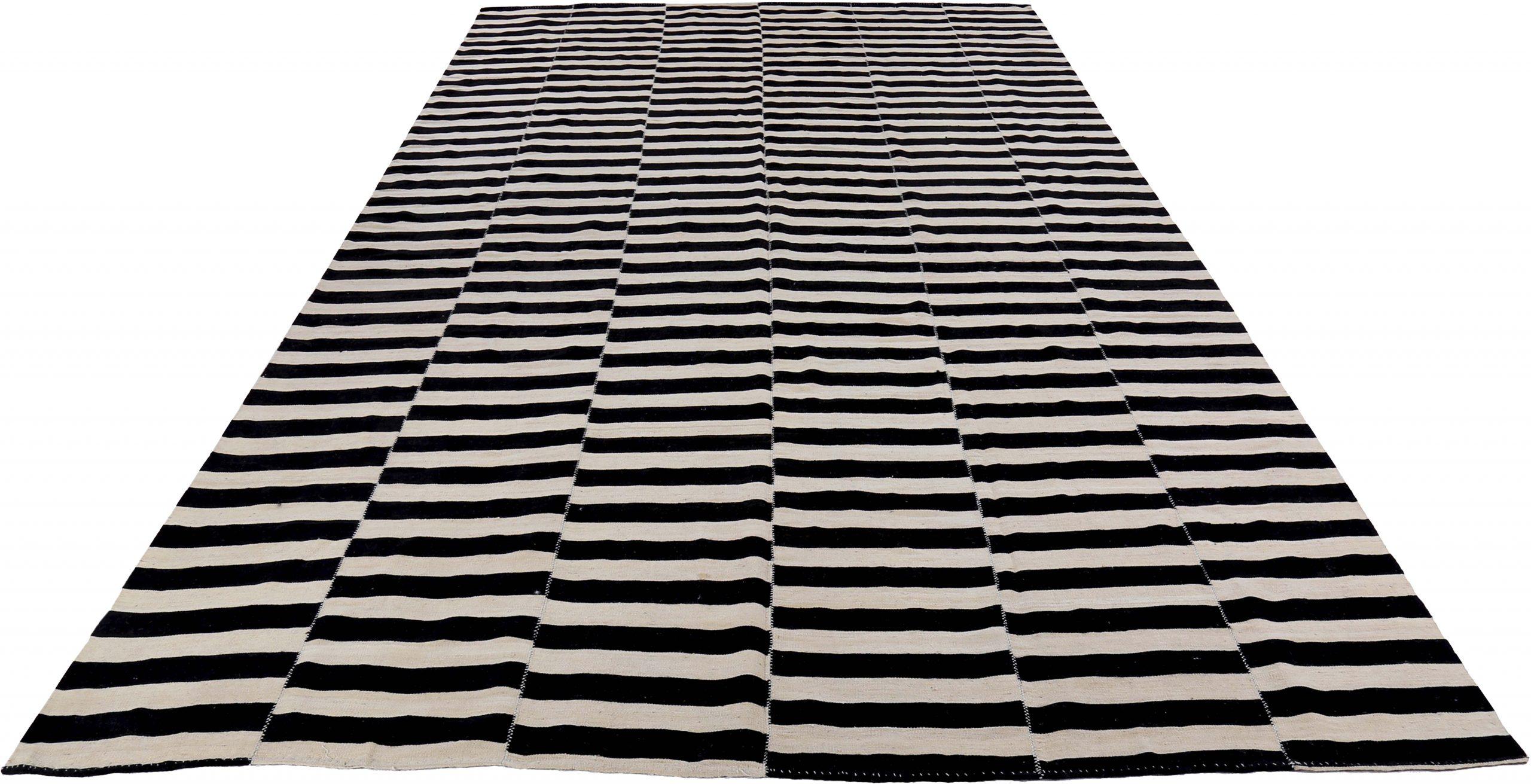 Scopri l'eleganza del Rug & Kilim persiano, caratterizzato da un tappeto over size del 1990. Progettato in lana e in bianco e nero, questo design esclusivo è perfetto per valorizzare il tuo spazio.