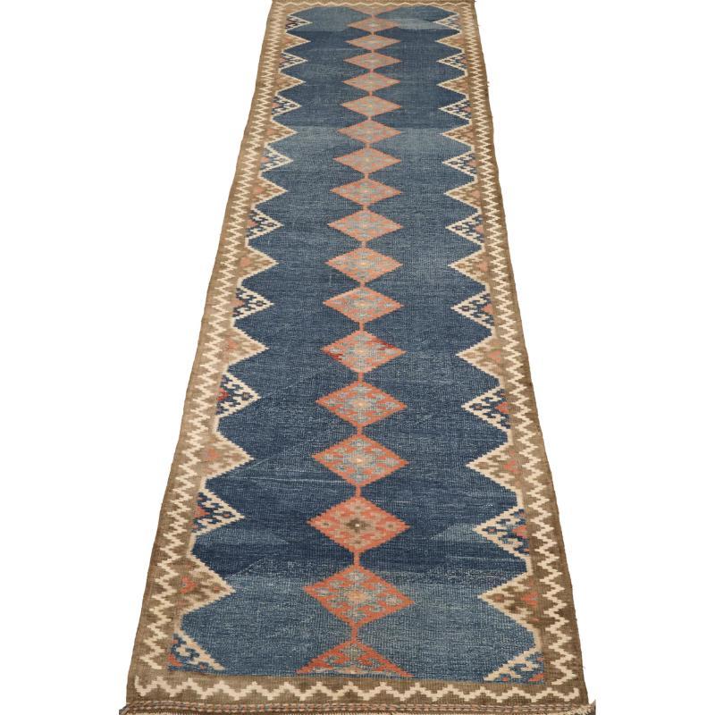 Entdecken Sie die Eleganz des persischen Kilim mit dem Läufer von CIRCA 1940. Dieses exklusive Design aus Wolle und BluePink ist perfekt, um Ihren Raum zu verschönern.
