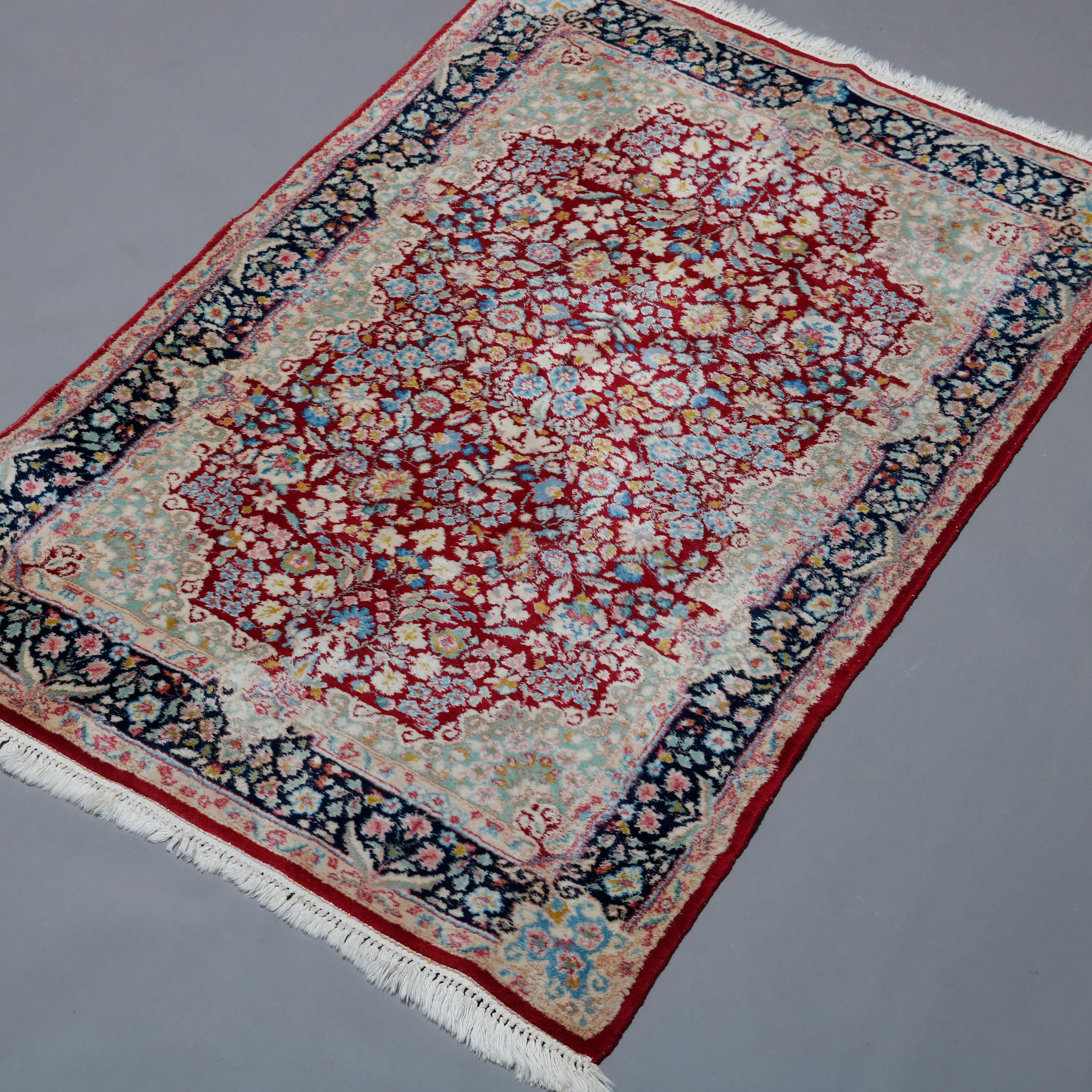 A Persian Kirman oriental rug offers wool construction with all-over floral and foliate design on red ground having elaborate shaped border, circa 1940.

Measures: 66.5