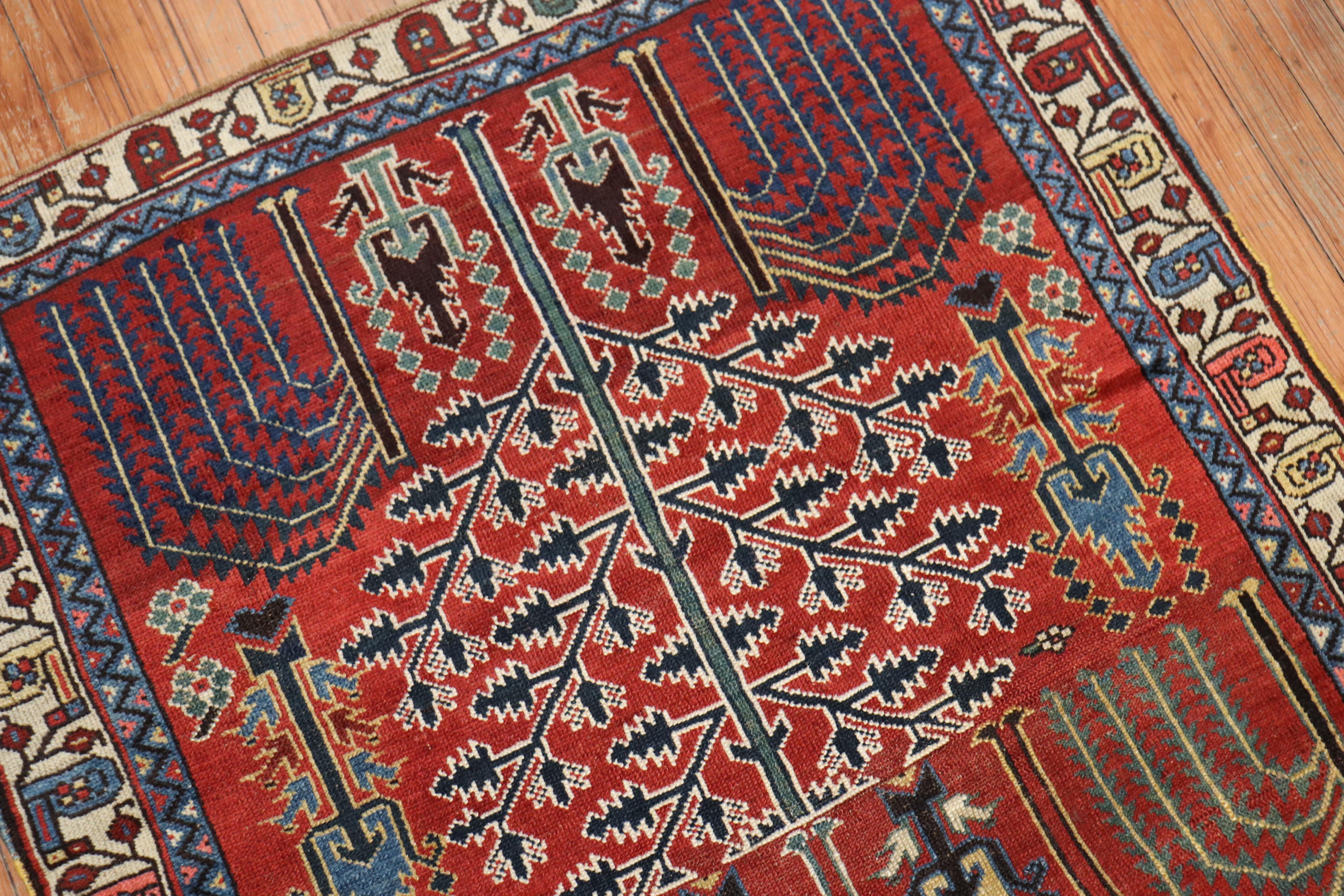 A colorful early 20th century Persian Kurd rug with a large scale weeping willow Tree motif on a rusty red ground

Measures: 3'5'' x 4'11''.