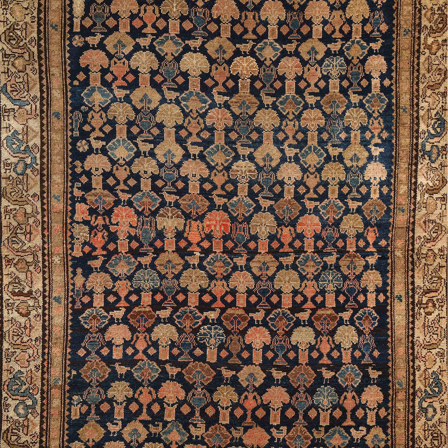 This Persian Malayer carpet circa 1900 consists of pure handspun wool and vegetable dyes. It is hand-knotted on a cotton warp and wool weft, featuring natural hues of indigo, gold, light blue, and orange amid neutral creams and tans. The colors have