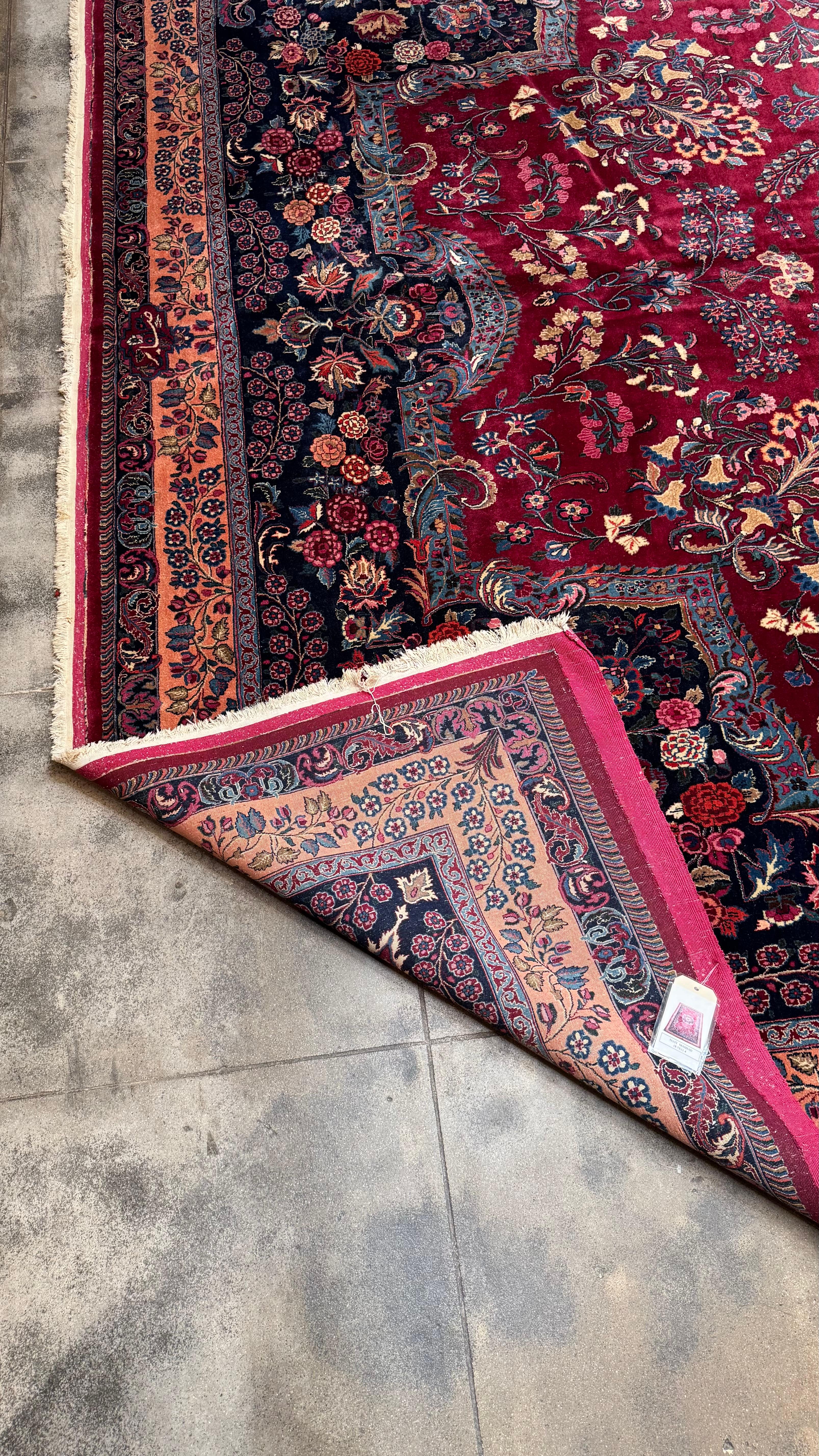Uno squisito tappeto persiano Mashhad di grandi dimensioni, annodato a mano nella città santa di Mashhad, nel nord-est dell'Iran. Questo pezzo mette in mostra un lussuoso campo rosso cremisi con un complesso medaglione centrale, circondato da