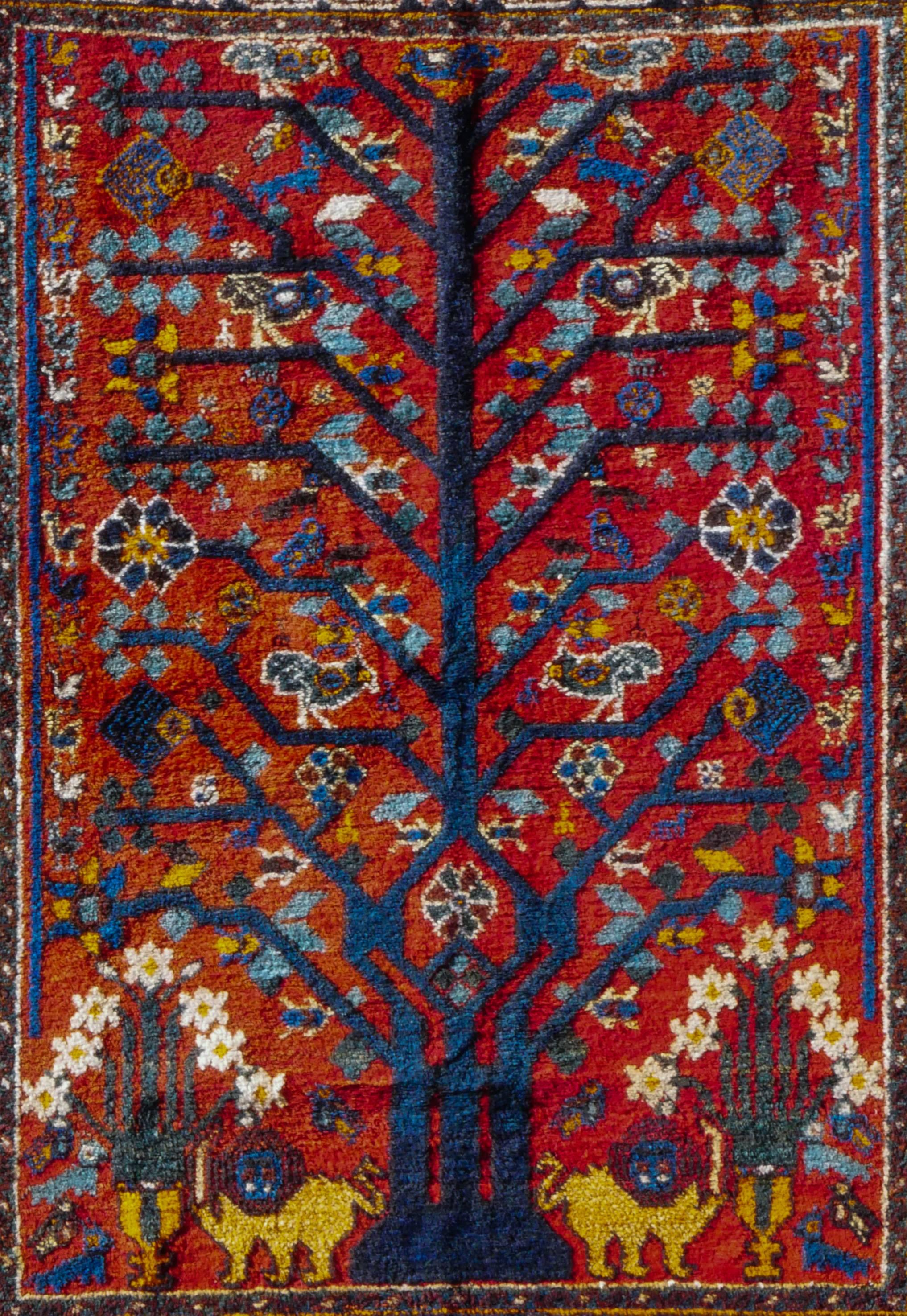 This is a nomadic masterpiece; a rare Tree of Life Neyriz gabbeh. Neyriz is a small town in Fars province in southwest Iran. Neyriz weavers seem partial to Qashqai mythology and frequently draw on their motifs. 
This is a small-format carpet with