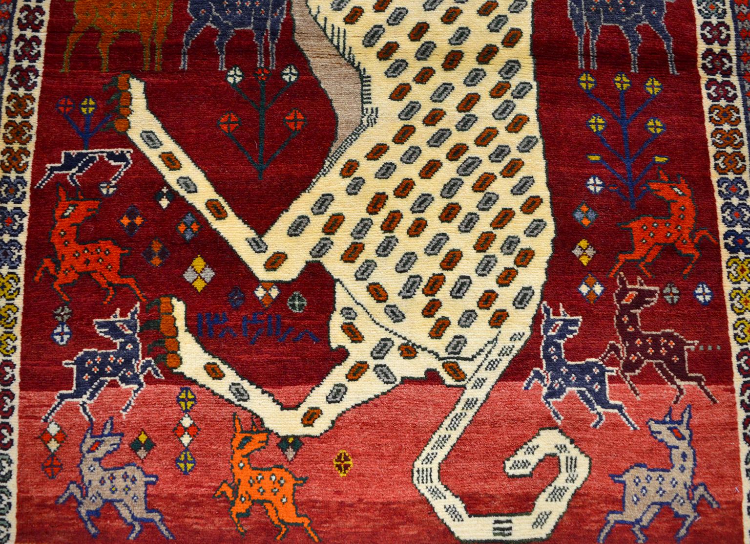 This Persian Qashqai Kashkouli leopard animal carpet, circa 1930 consists of pure handspun wool and organic vegetable dyes. The leopard’s predominately cream colored coat provides contrast against the deep reds of the field, which is decorated with