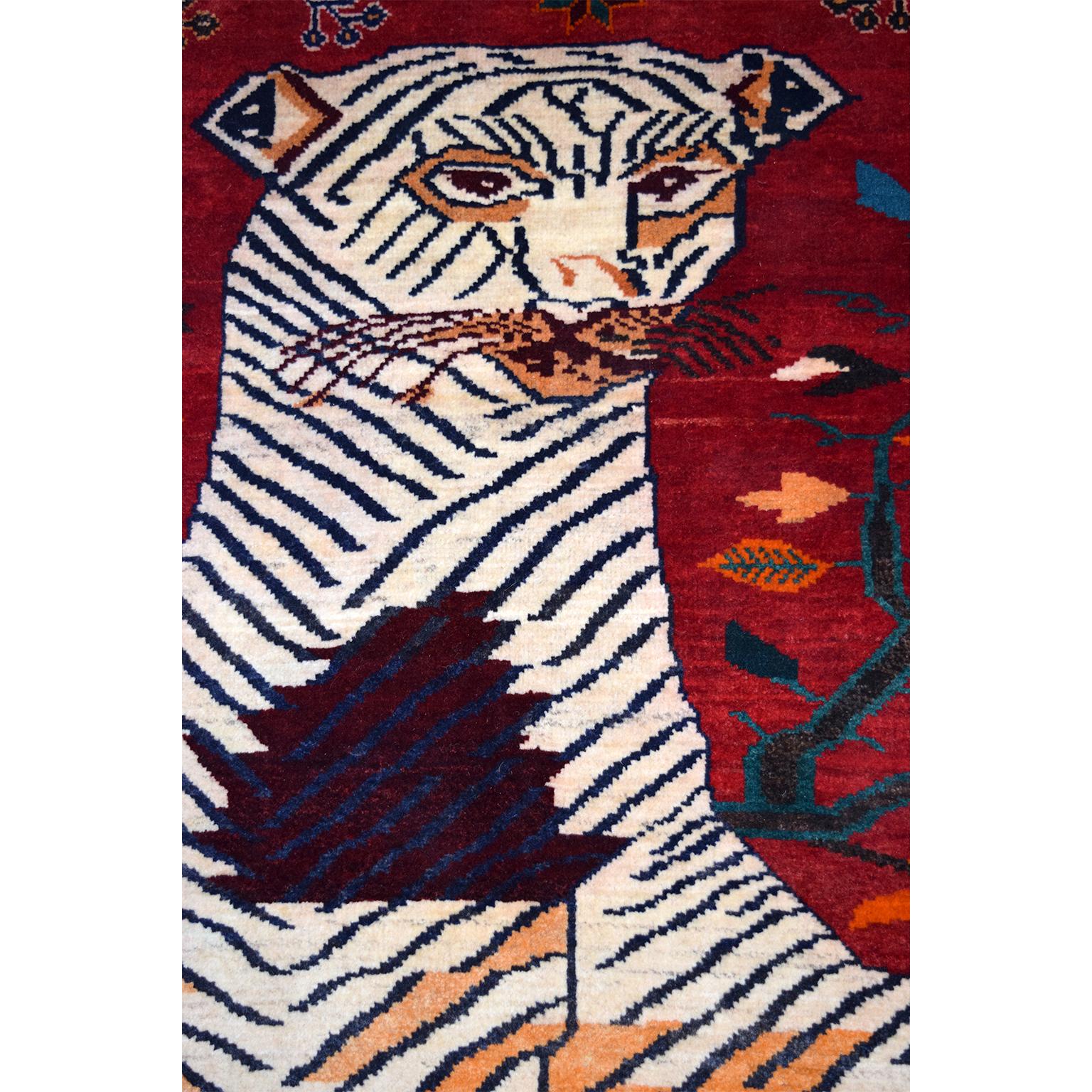 This Persian Qashqai Tiger carpet in pure handspun wool and vegetable dyes circa 1940 exhibits a colorful tiger design in reds, oranges, golds, blues, and cream. The figure of the tiger dominates the field, balanced by geometric floral motifs