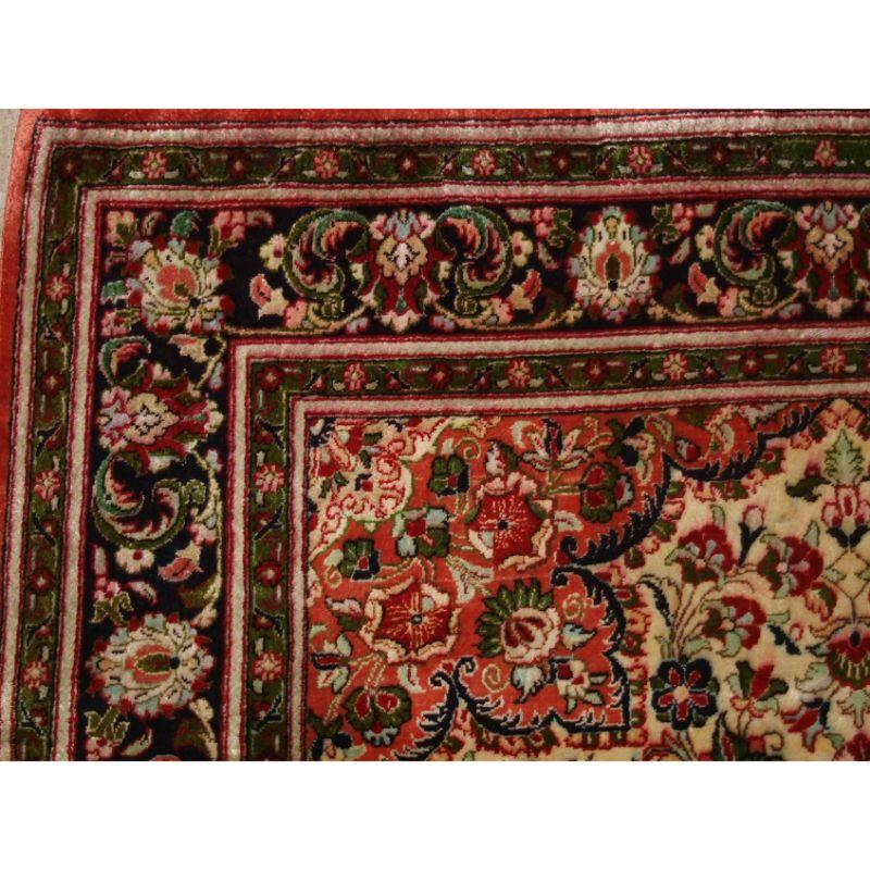 A good example of a small size Persian Qum silk rug with fine weave and a pleasing floral medallion design.

The rug has an ivory field decorated with floral sprays around the central indigo blue medallion. The dark indigo border has a classic