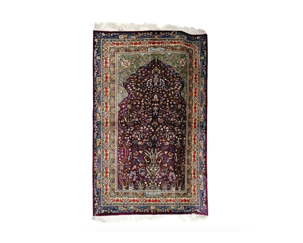 A highly decorative hand knotted Qum Persian silk carpet by Rajabian. The carpet depicts traditional Persian design with a vase and flowering plant branches on the burgundy ground. The carpet has a large number of shades and very good detail. Signed