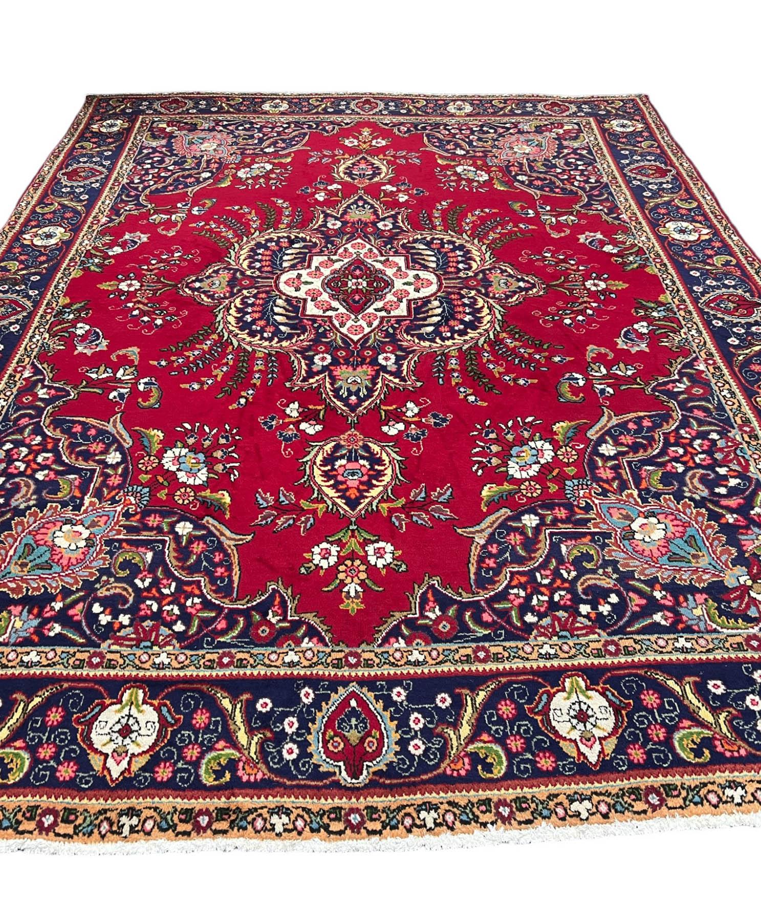 A stunning vintage Persian Tabriz. The rug boasts a combination of vibrant reds complemented by accents of blues, greens, and subtle muted yellows. The intricate patterns and rich colors effortlessly create an inviting focal point, adding warmth and