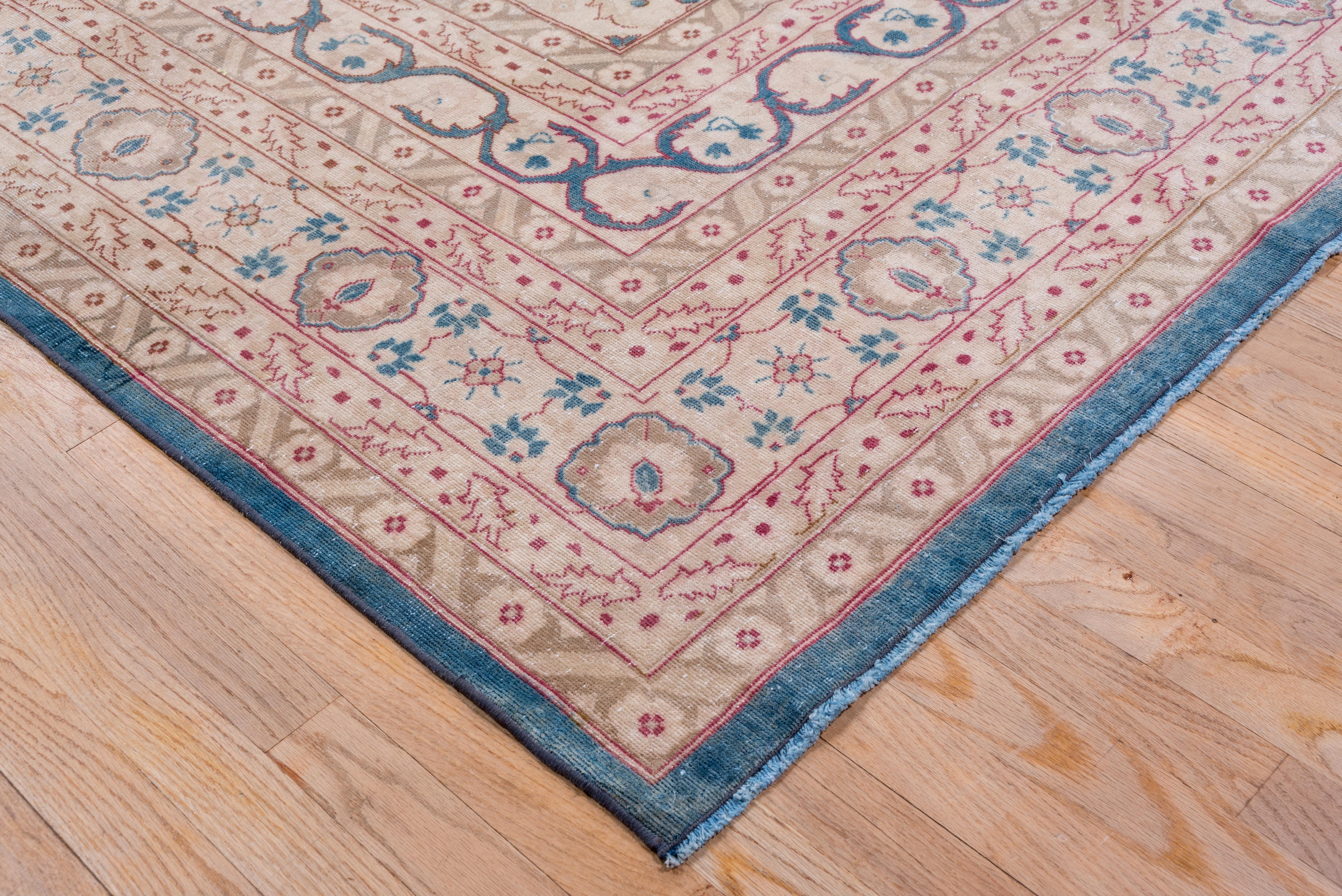 This NW Persian finely woven city carpet presents a lightly lobed off white medallion on a denim blue ground with delicate flower sprays in each corner outside of off white quarter medallion corners. S-scroll inner border.
