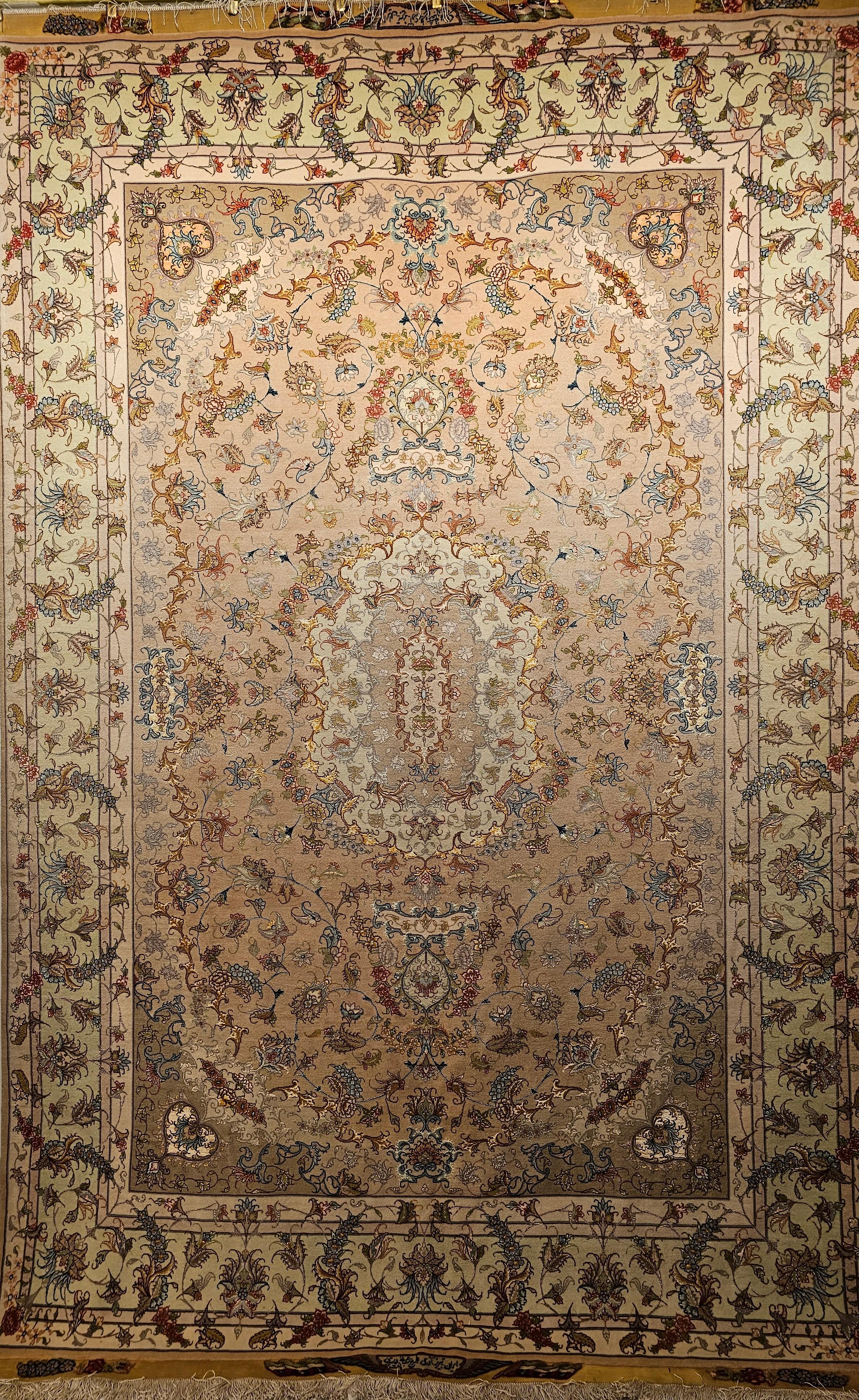 A beautiful and very fine and artfully hand woven authentic Persian Tabriz with a floral design with silk foundation.  This Tabriz room-size rug has a very fine design and weave.  It has a pale camelhair/taupe color field with a light green color