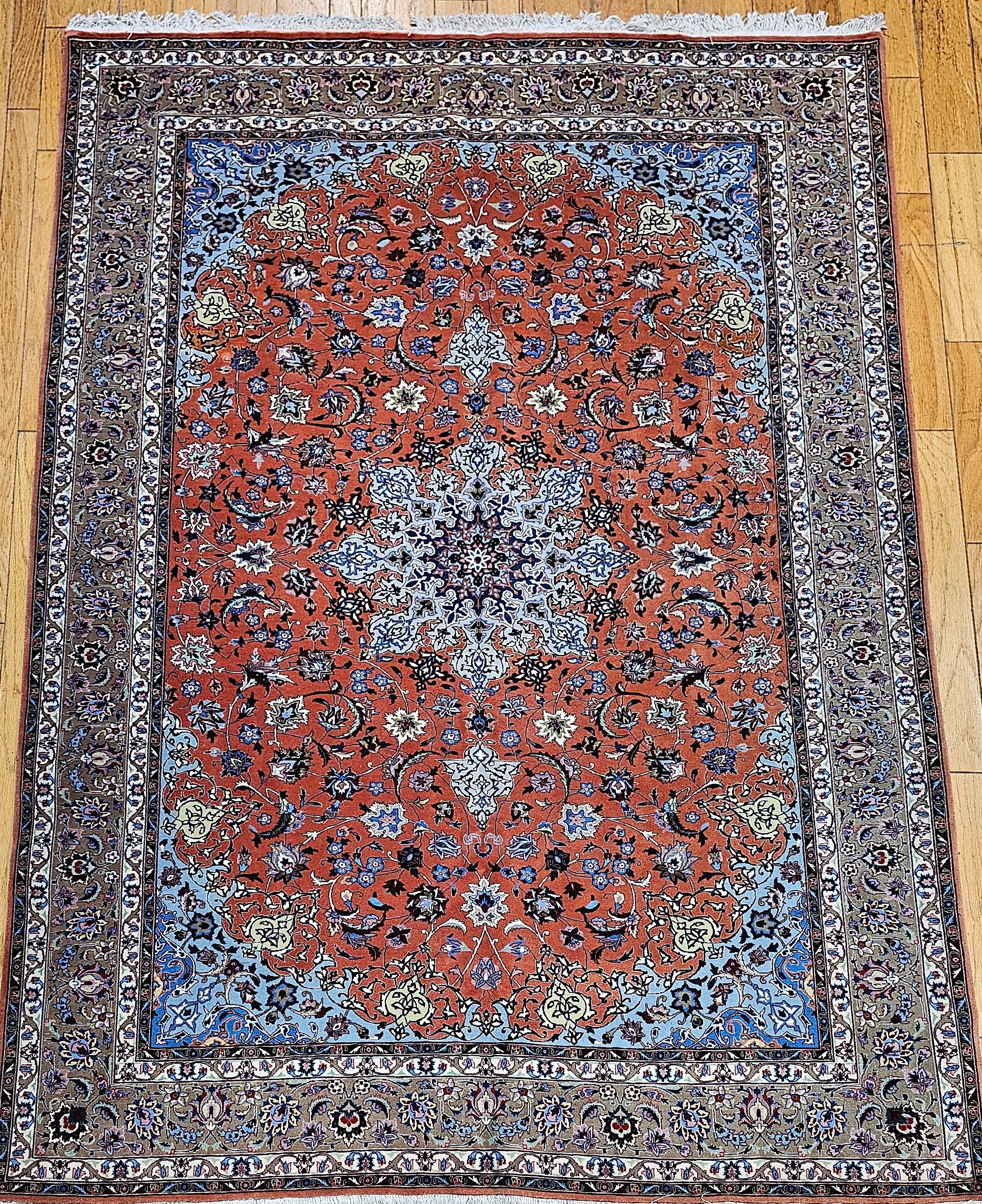 Exemple exceptionnel de l'artisanat persan, ce tapis Tabriz de belle taille présente un motif floral richement détaillé, tissé dans un champ rouge rouille éclatant, élégamment encadré par une bordure marron clair aux tons caramel. Tissé à la main