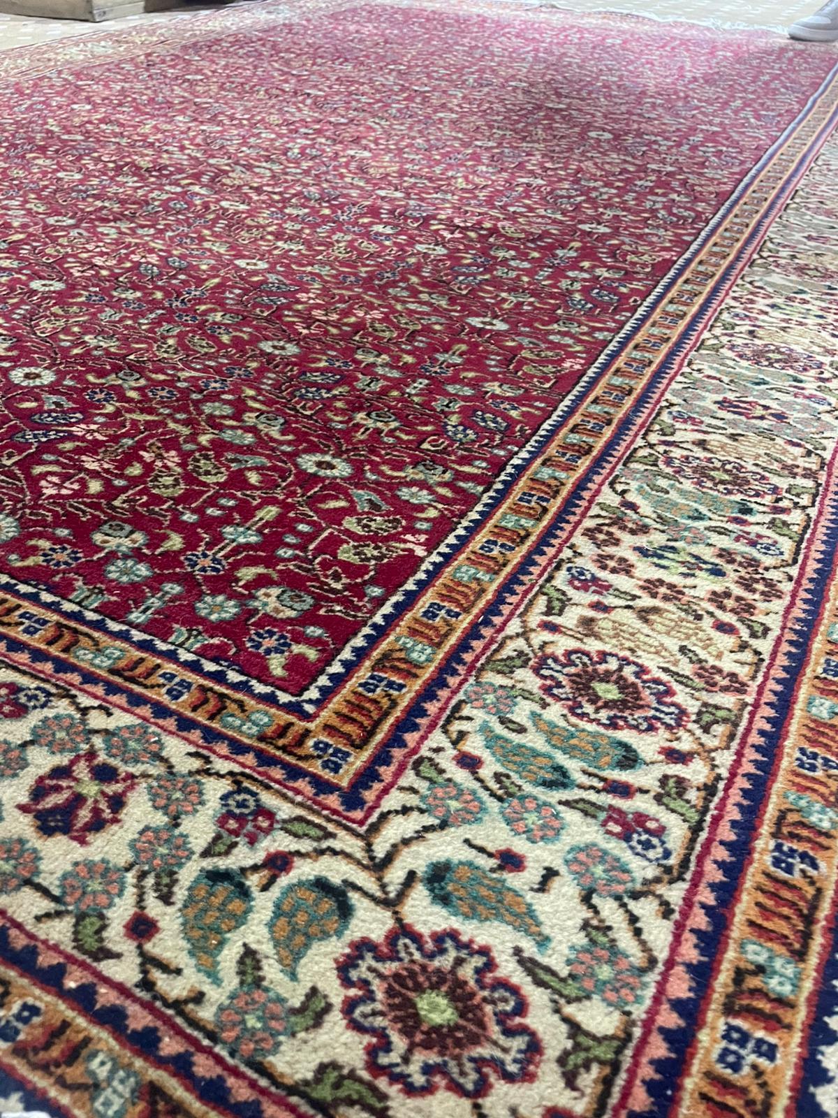 A stunning example of refined Persian craftsmanship, this elegant hand-knotted Persian rug features a classic all over floral pattern in a rich crimson red field, bordered by intricate ivory and gold vine scrolls. Likely originating from the weaving