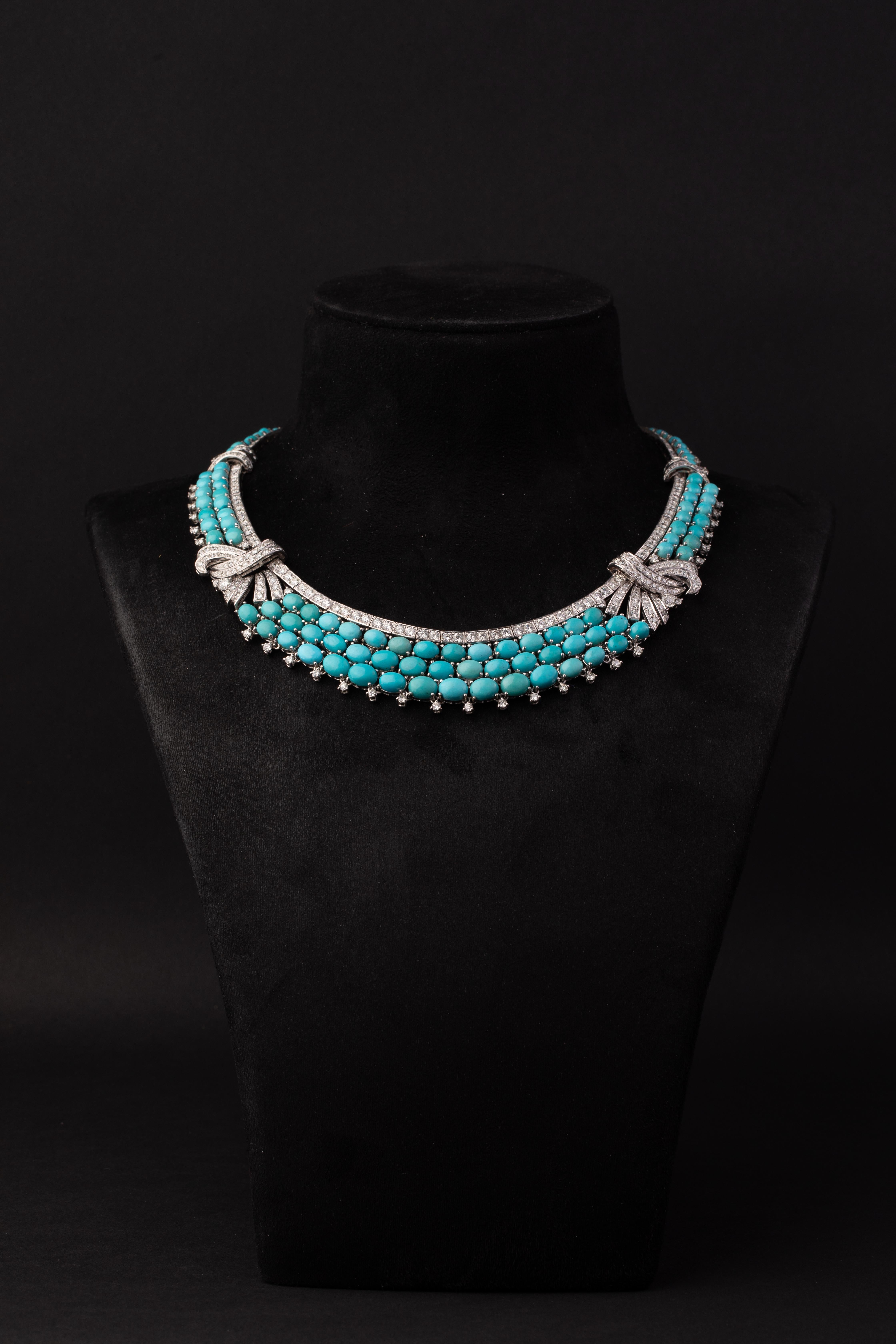 An elegant Persian Turquoise and Diamond Necklace designed as graduated rows of oval cabochon Persian turquoise, accented with stylised bow motifs set with brilliant-cut diamonds, further highlighted by diamond-set borders and fringe detailing.