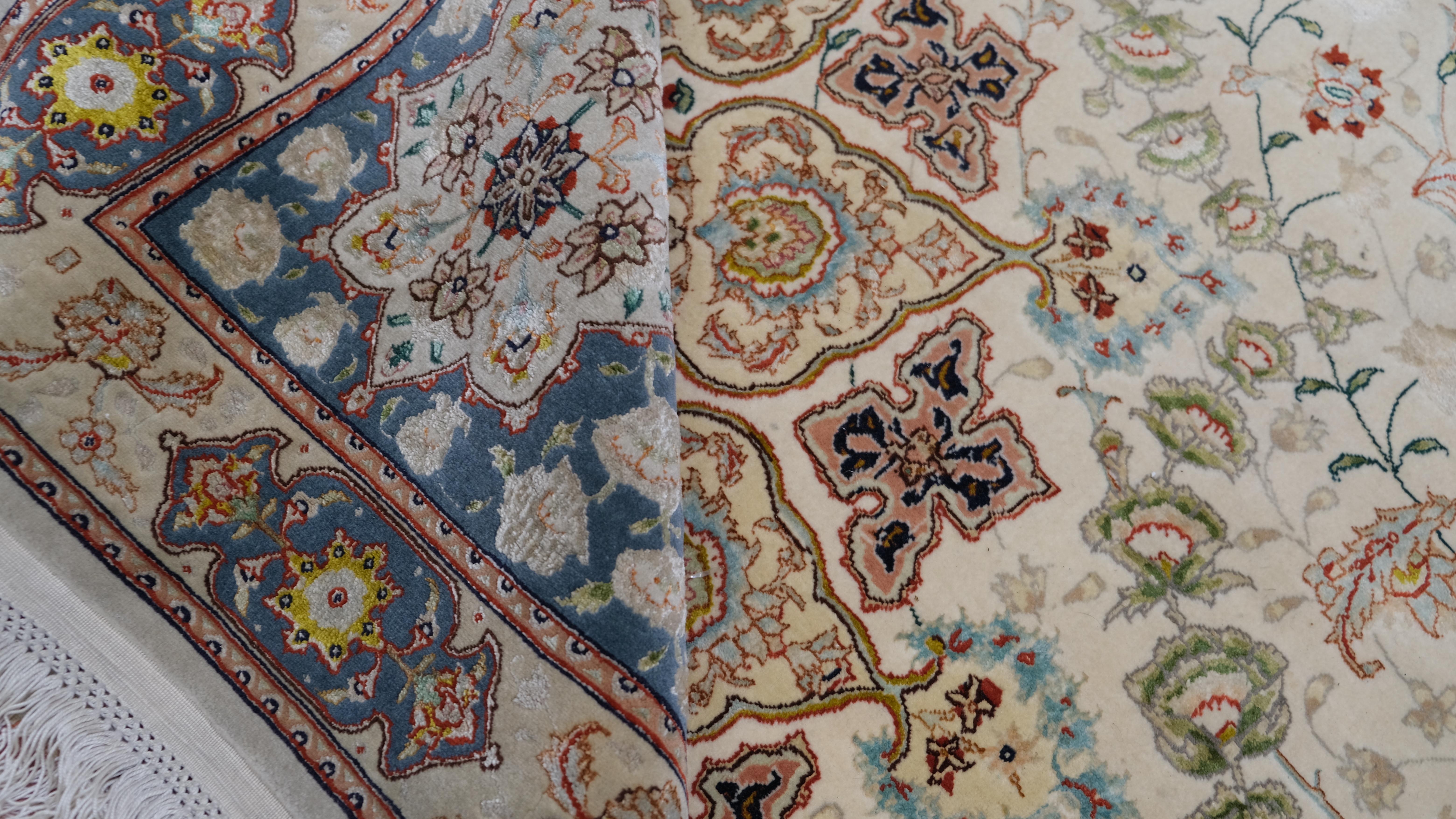 Add a touch of timeless luxury to your home with this exquisite hand-knotted rug, expertly crafted from a blend of premium wool and silk. This stunning piece features a meticulously detailed central medallion surrounded by intricate floral patterns,