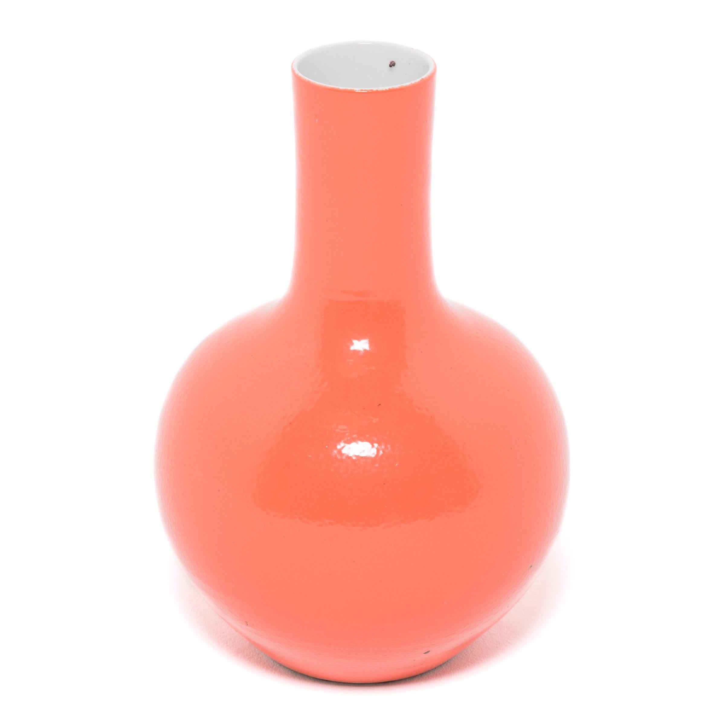Drawing on a long Chinese tradition of ceramics, this striking long-necked vase is cloaked in an all-over persimmon-orange glaze. With a rounded, globular body and cylindrical neck, the large vase reinterprets the traditional gooseneck shape known