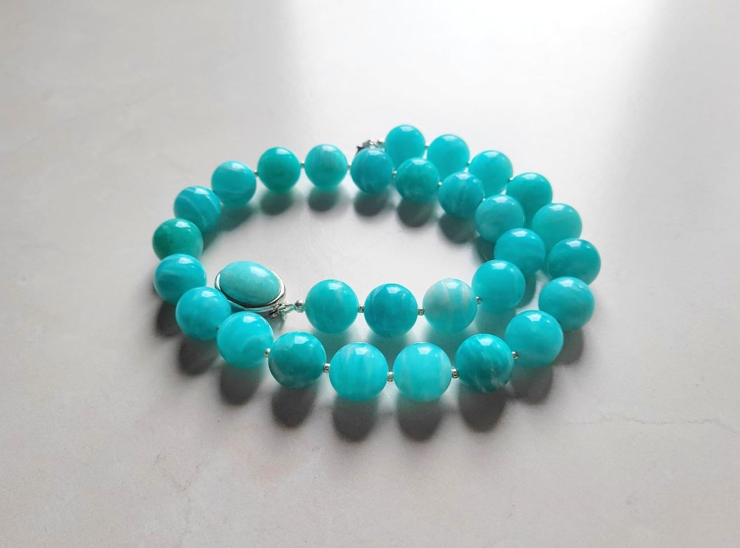 The necklace is 18 inches (45.7 cm) long, and the smooth round beads are 14 mm in size.
The beads are sea blue and turquoise, with very subtle soft streaks. We are guaranteed 100% natural Peruvian Amazonite, not treated in any way. The beads are