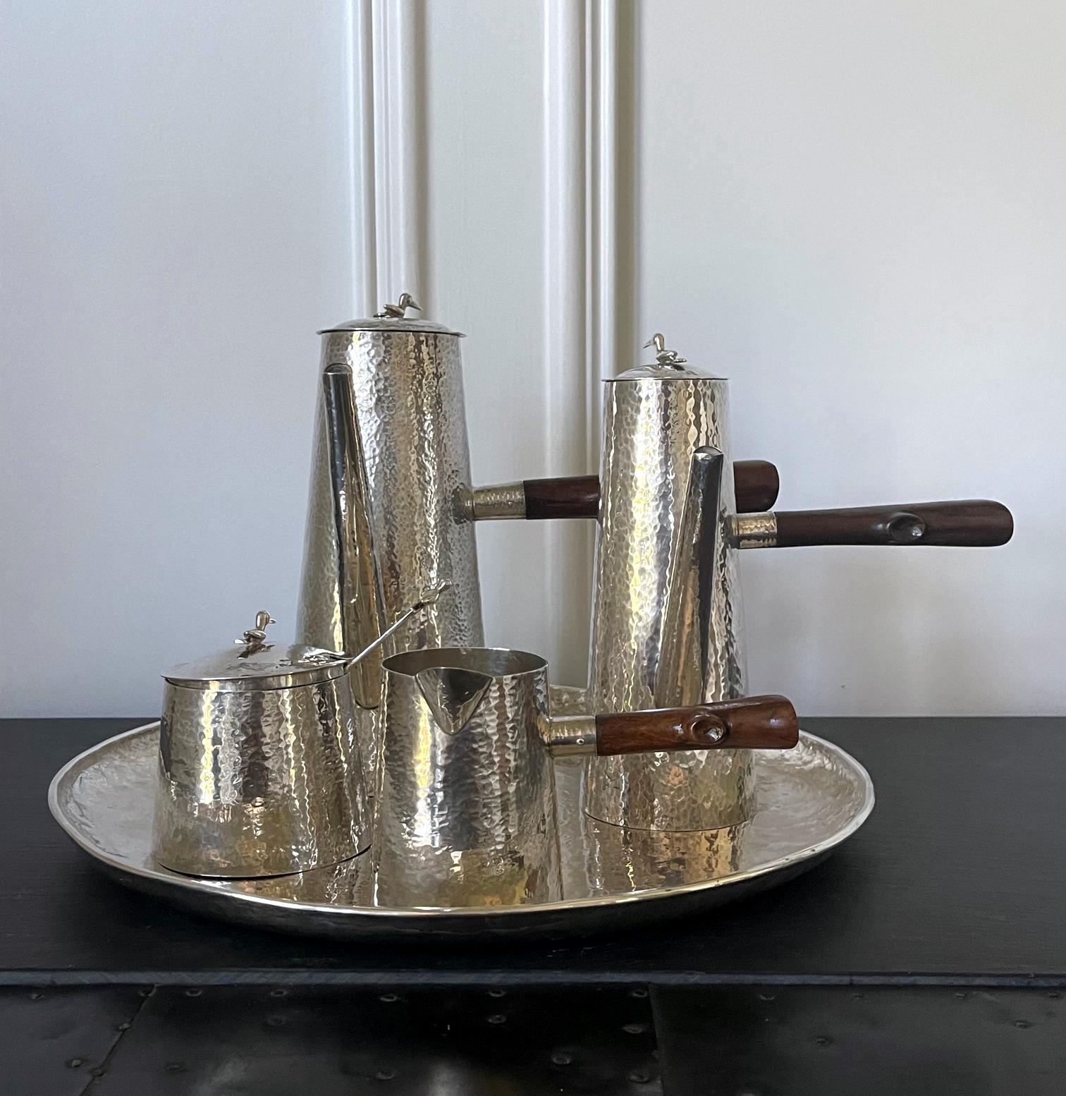 A sterling silver coffee service set consists of six pieces: a coffee pot, a chocolate pot, a covered sugar bowl with a serving spoon, a creamer and a round tray. Made in Peru circa mid to second half of 20th century, maybe 1970-80s, this modernist