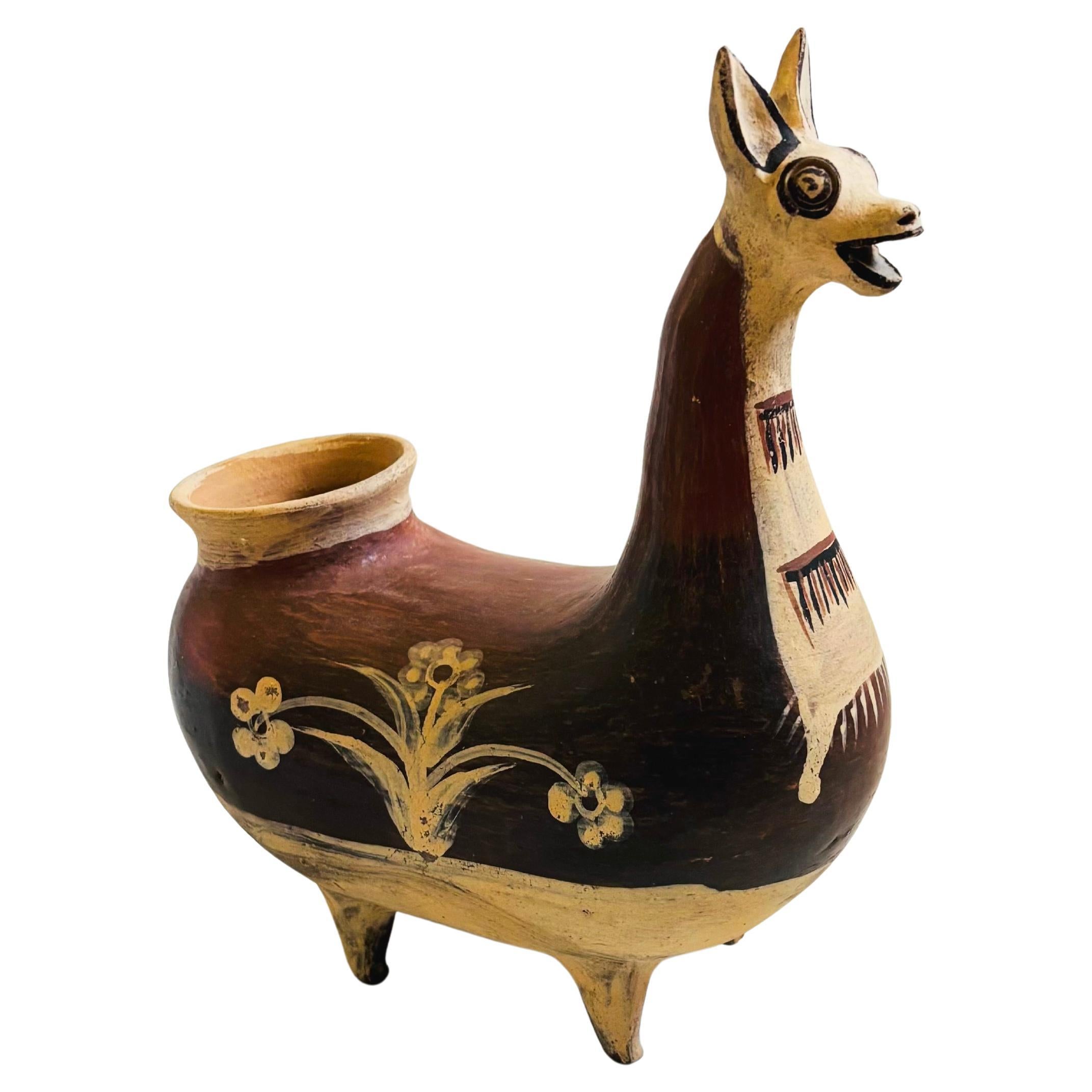 A vintage Peruvian folk art pottery vase in the shape of a llama. Decorated in lovely hand painted designs in tan and terra cotta. 

