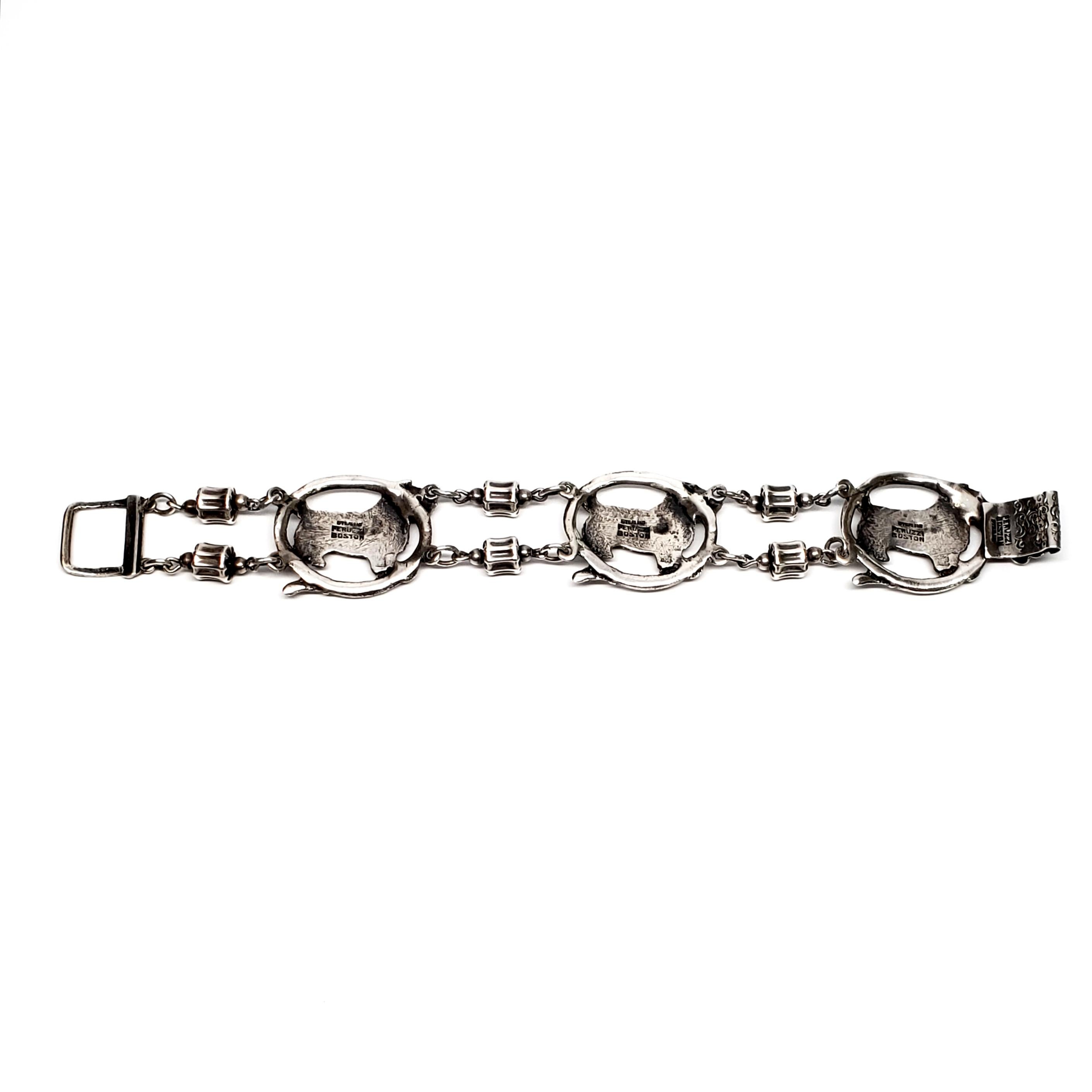 Vintage sterling silver link bracelet by Peruzzi of Boston.

This pretty bracelet is compromised of 3 panels depicting a small terrier type dog inside an oval belt or leash connected by double barrel beads.

Measures approx 7 1/4