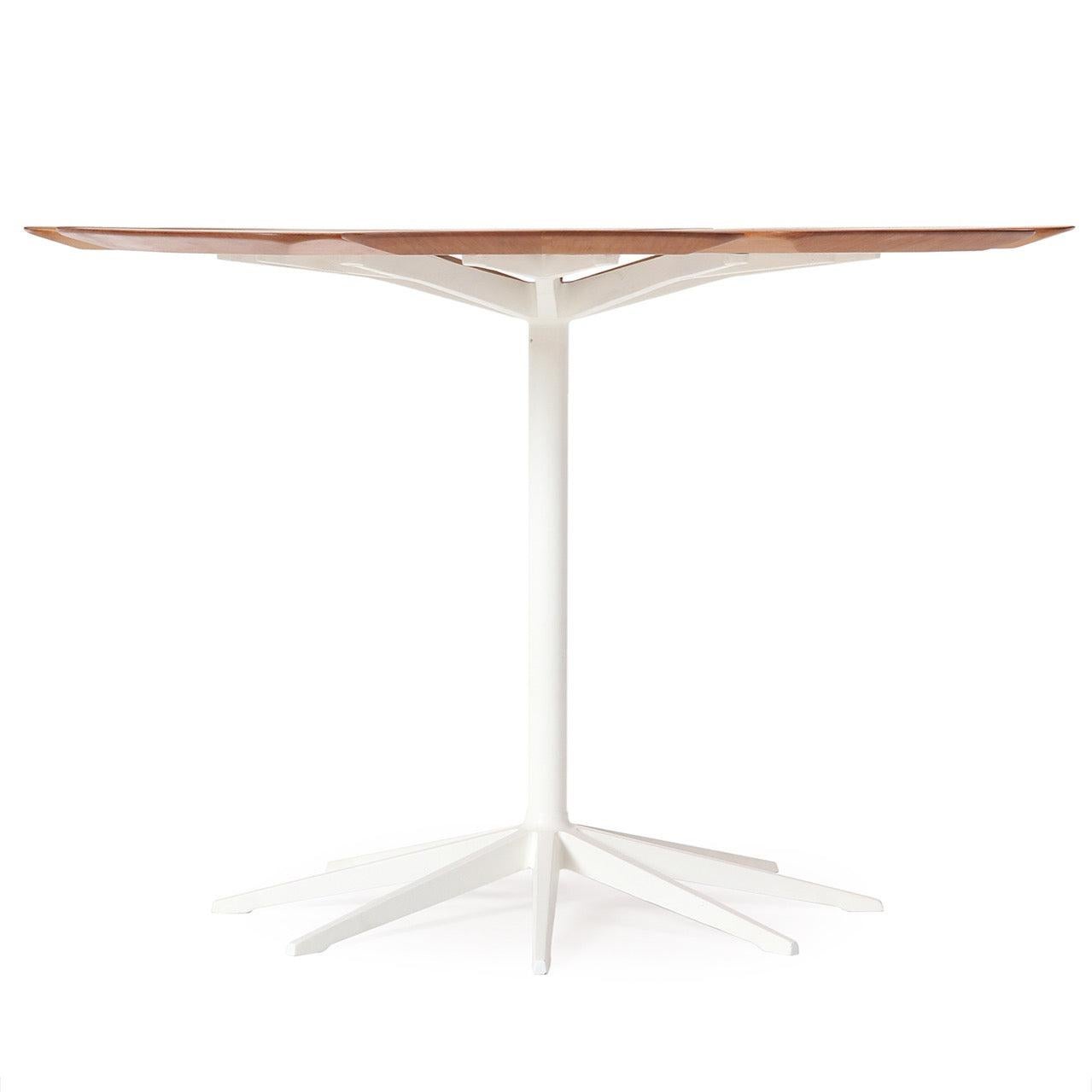 A 'petal' dining table with a flower-like pine top on a white enameled eight-point cast iron pedestal base. Pine petals made by the workshop.