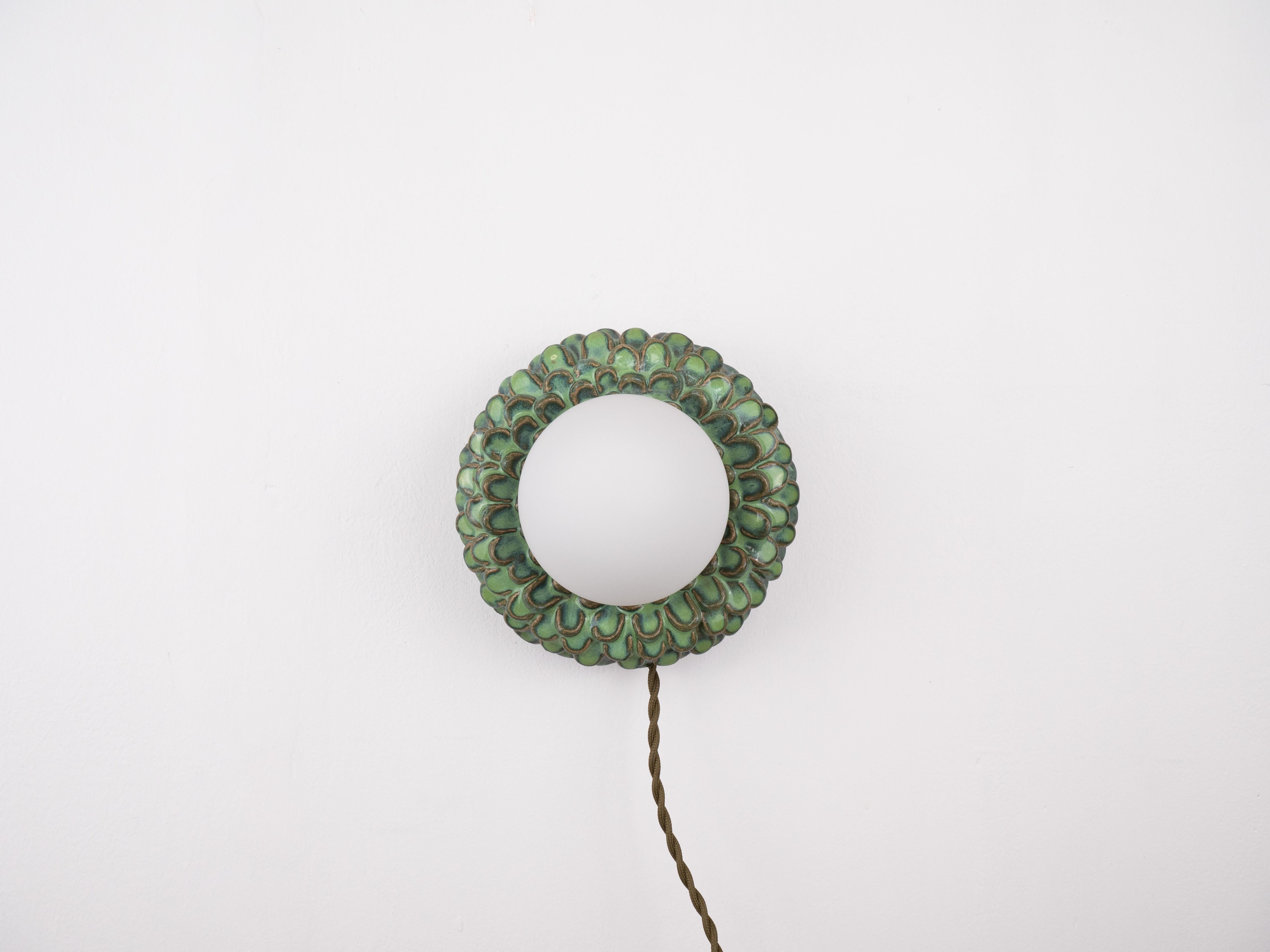 Este aplique de cerámica hecho a mano tiene el diseño más encantador en forma de flor con un centro brillante que añadirá un toque cálido a cualquier espacio. Con sus delicados y brillantes pétalos, es una divertida mezcla de extravagancia y