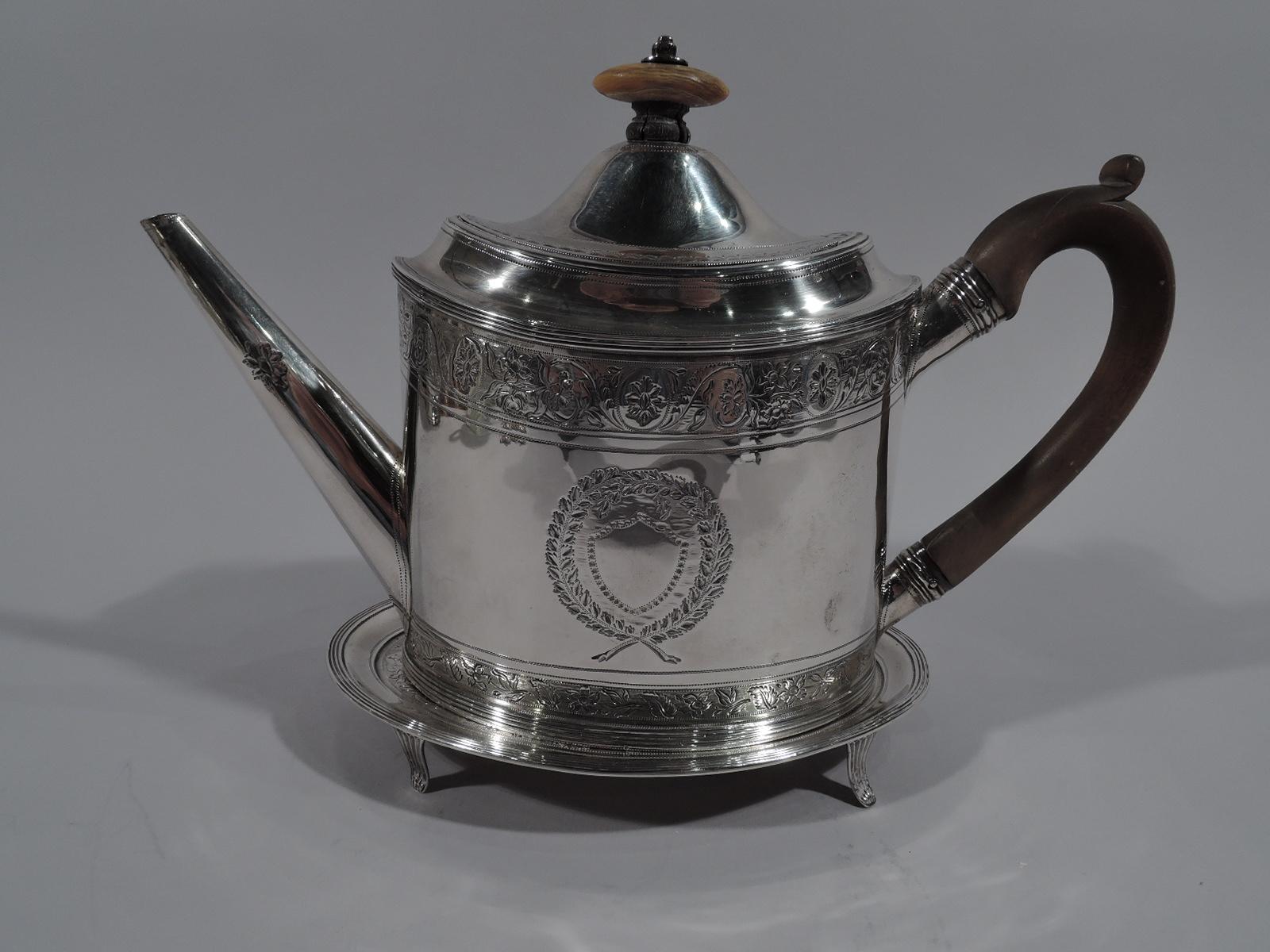 Rare George III sterling silver teapot on stand. Made by Peter & Ann Bateman in London in 1795. Teapot: Oval body with diagonal spout, hinged and domed cover with wood finial, and capped and high-looping stained wood handle. Stand: Oval with four