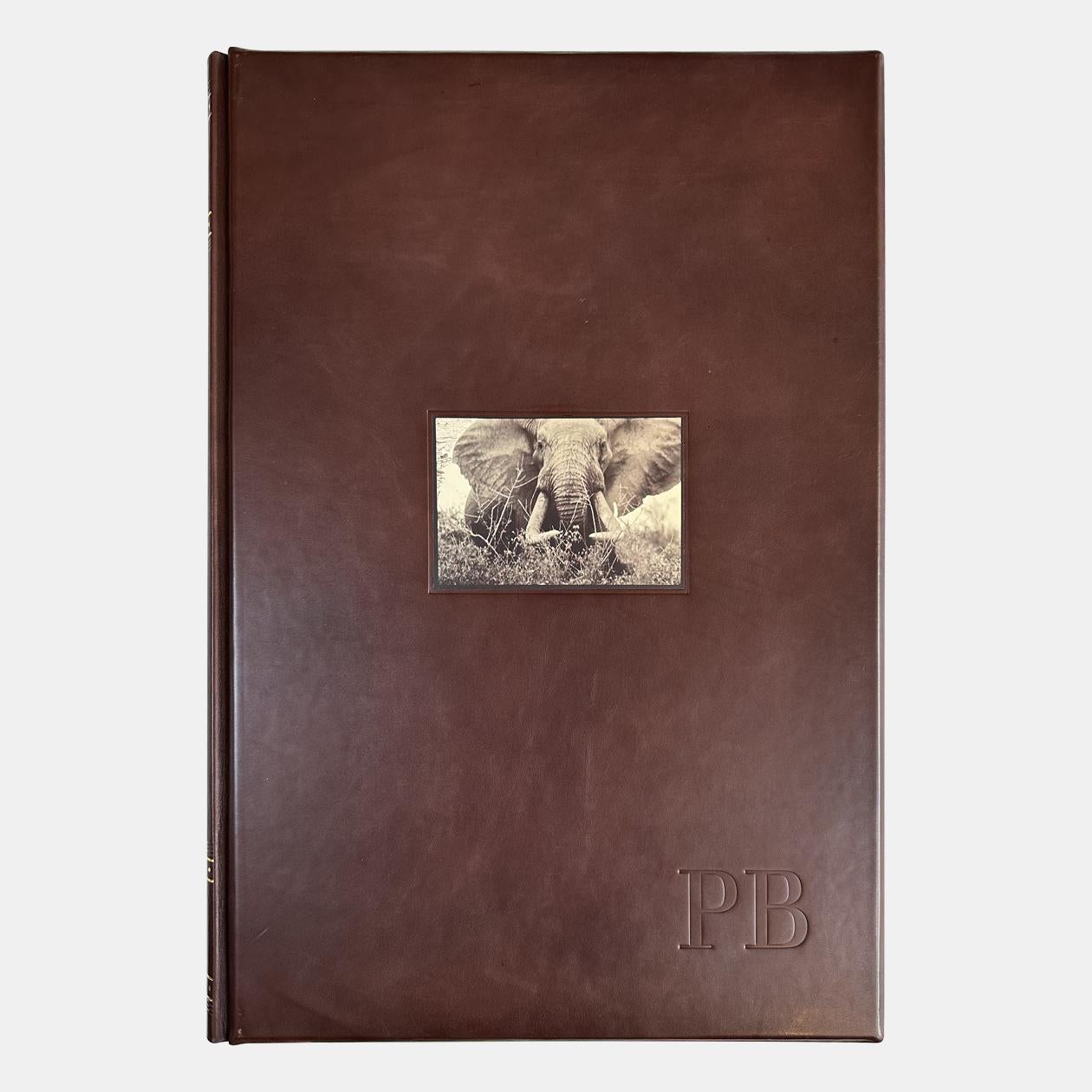 LOT:20230825S02
Peter Beard 
[Peter Beard,  Collector's Edition "965 Elephants"]
Leather-bound hardcover; gelatin-silver print photograph; velvet-lined wood shipping crate
Hardcover: Artist signed and numbered 0158 on the page (Edition 158 of
