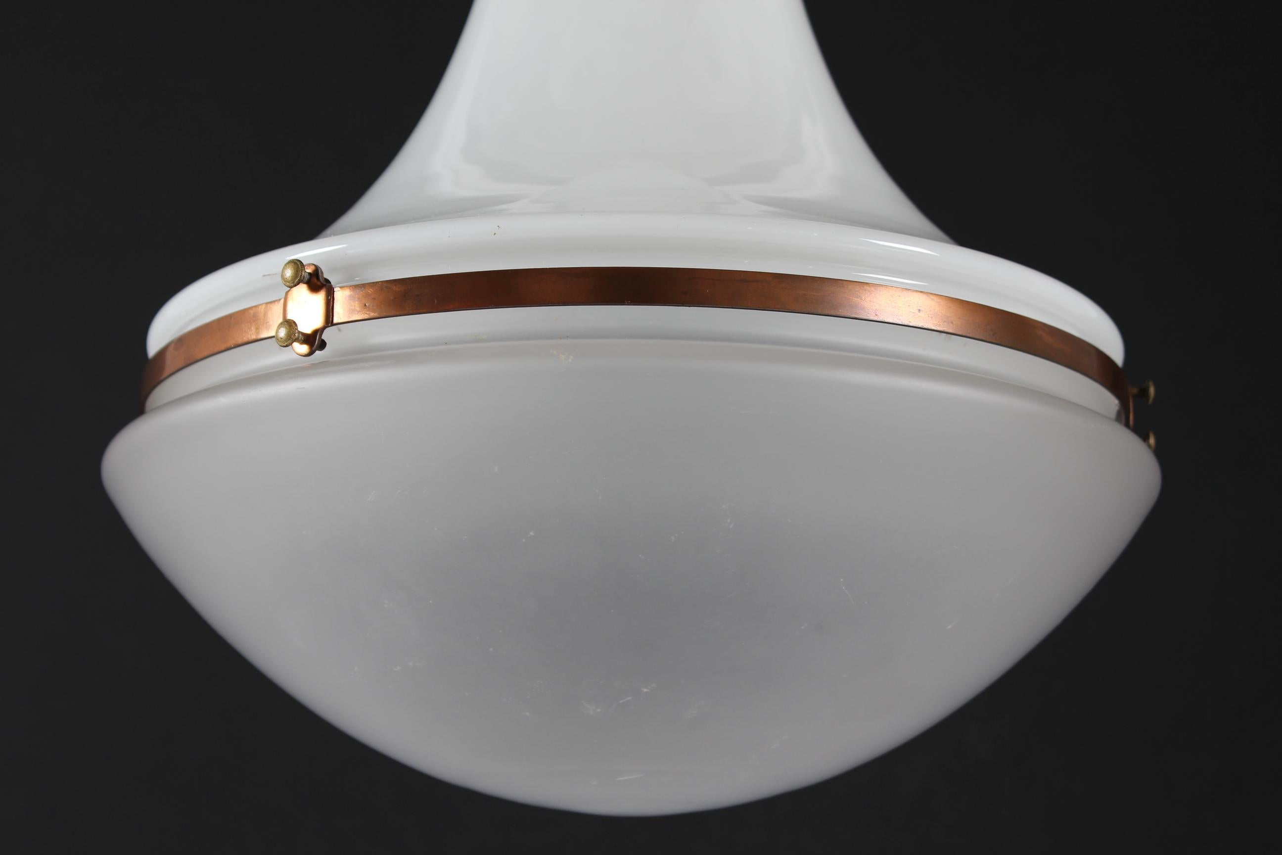 Large version Luzette pendent designed by Peter Behrens in 1908 for Siemens-Schuckert.
The pendant has a combined lower shade of frosted glass with upper shade of milk white opaline glass. The shade has copper fittings.

Measurements:
Height ca.