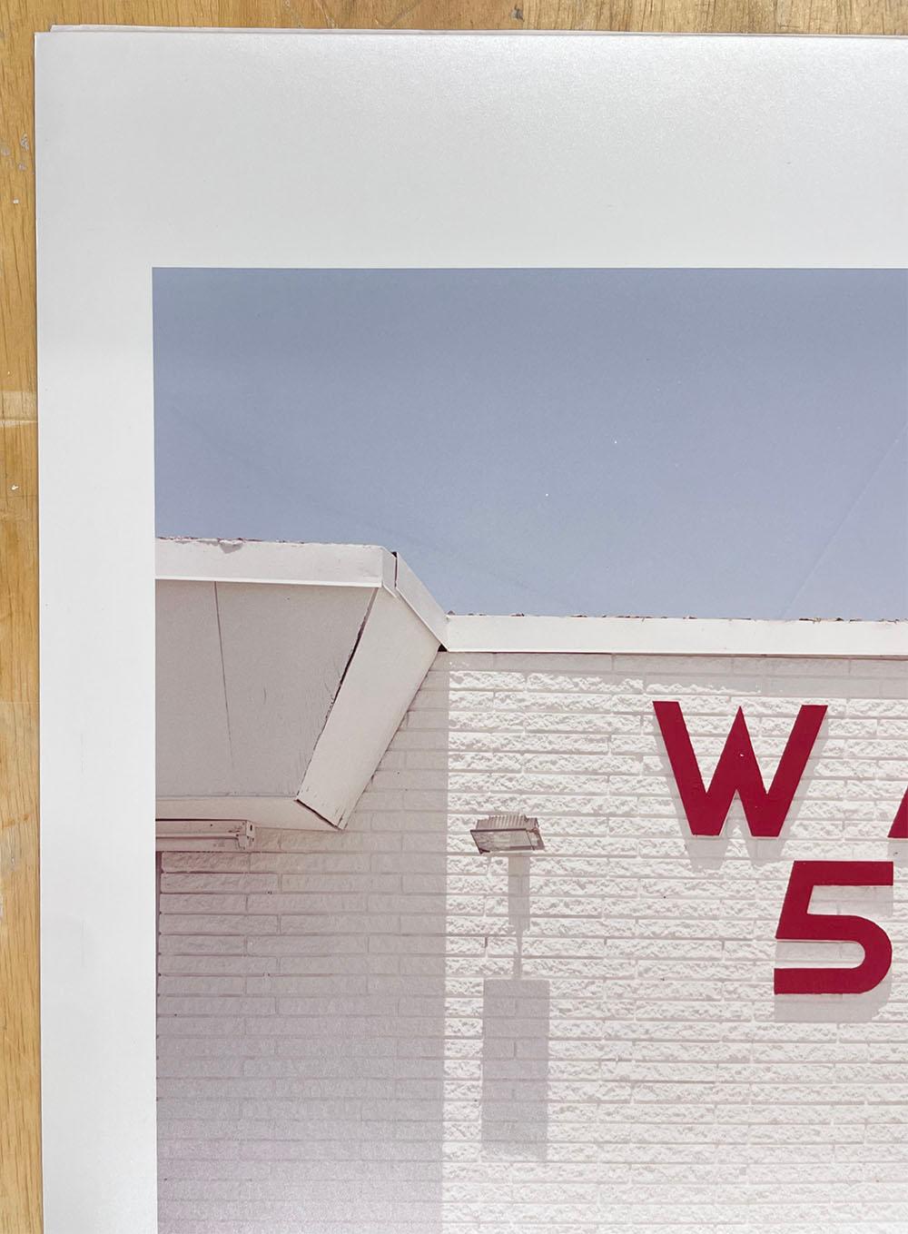 Wash 50 cents - Glaveston Bay, Texas, white building with red text, architecture - Gray Color Photograph by Peter Brown