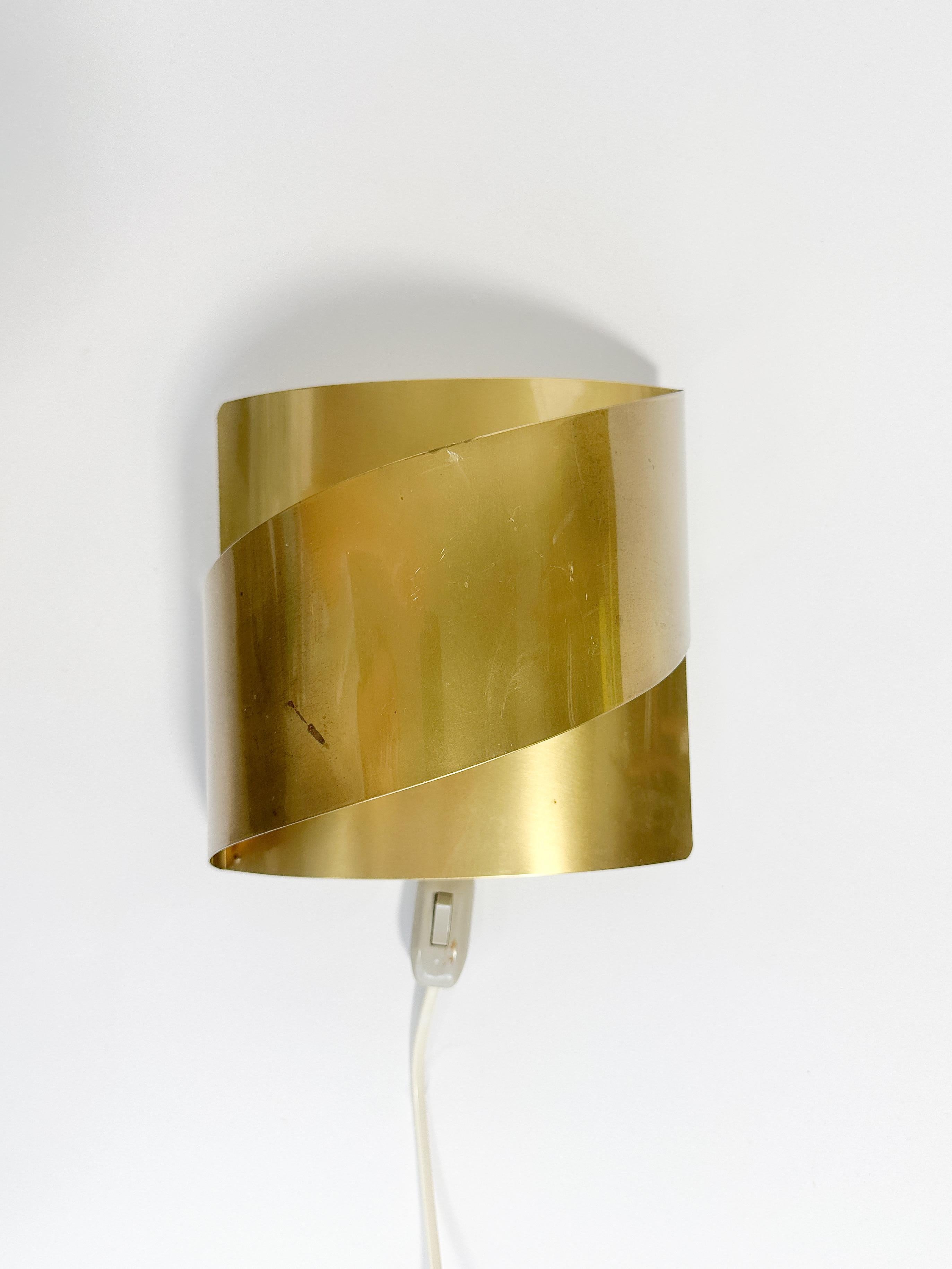 Brass wall light by Peter Celsing for Falkenberg in Sweden, model ‚Band‘, made in the 1970s.

Made of a solid brass sheet with a subtle patina, original ceramic socket. Remains the manufacturers sticker on the back.

Currently wired with a switch,