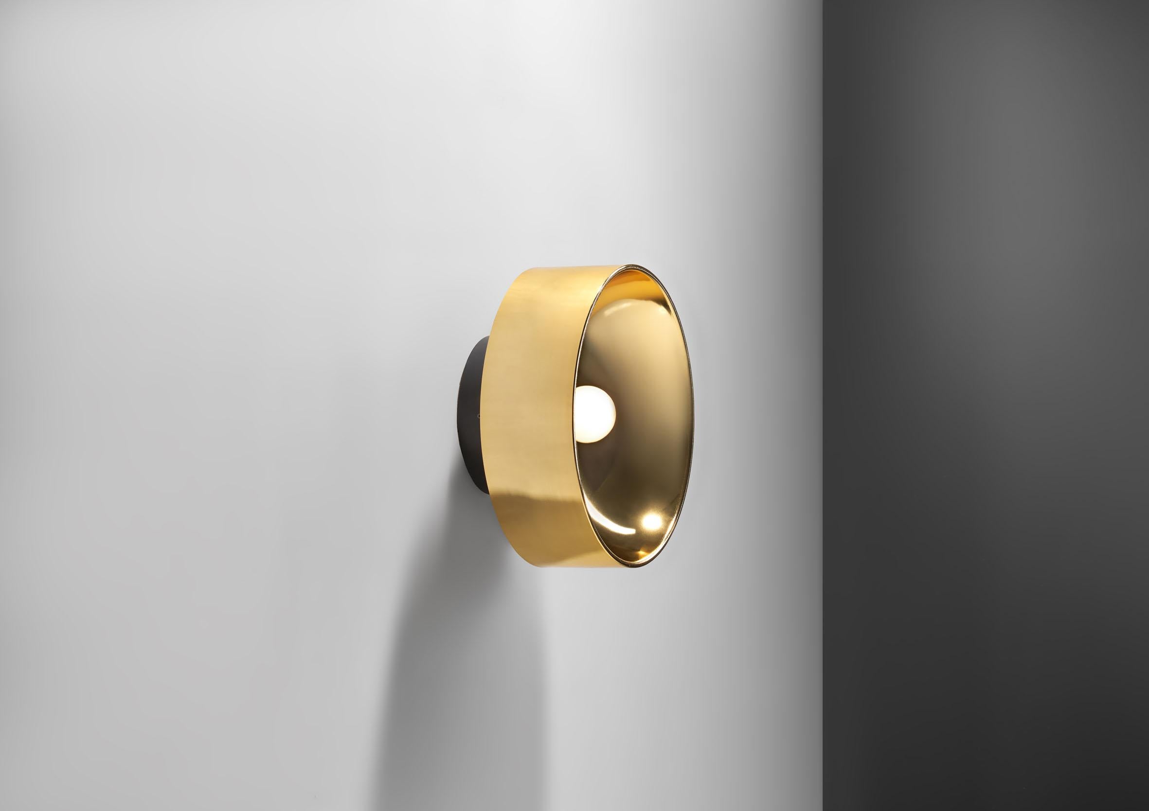 This stylish wall scone was designed by Peter Celsing for Falkenberg in 1966 for the cultural center Kulturhuset in Stockholm. 

The modernistic look is achieved by simple, yet smart design of the silhouette. The yellow brass body gently reflects