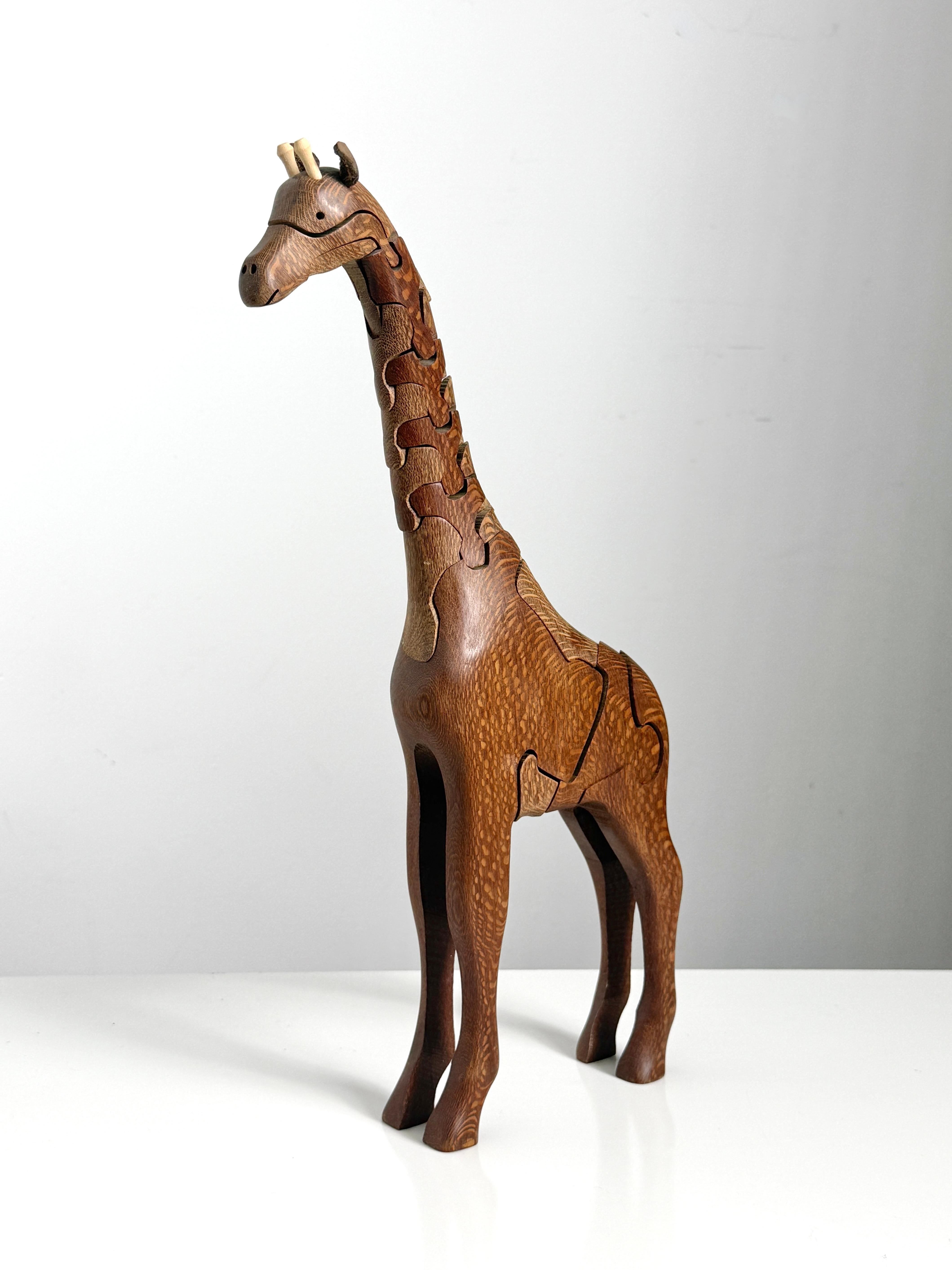 Giraffe puzzle sculpture in leopardwood by Peter Chapman 2006

Constructed of interlocking wooden puzzle pieces with articulating movement and a baby giraffe piece hidden inside

Ossicone pegs serve as the final securing element 
A really unique