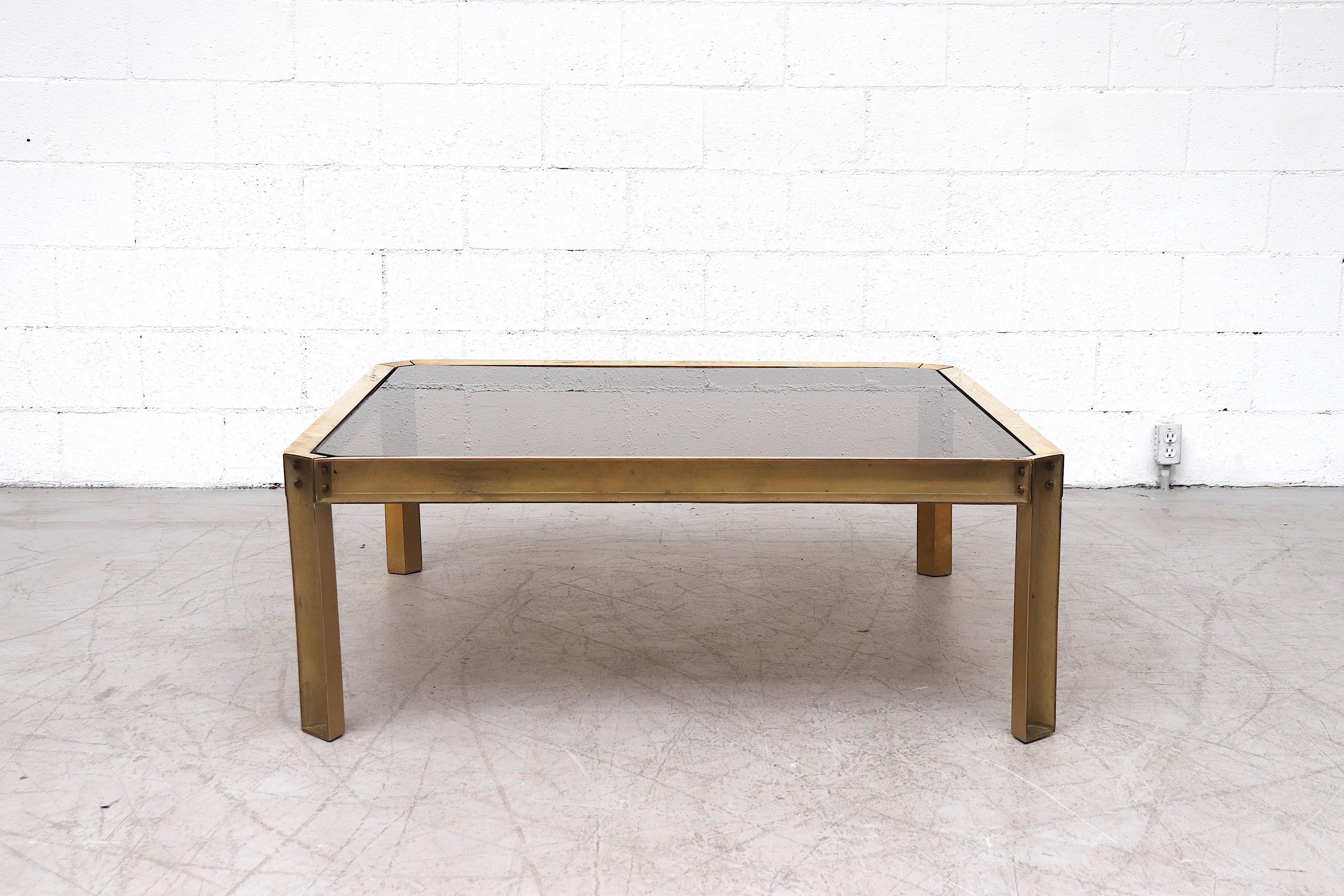 Industrial style brass and smoked glass coffee table with a raw construction look. Original condition with nice Patina. Peter Ghyczy studied architecture with an industrial design background at the Polytechnic University Aachen, and is recognized