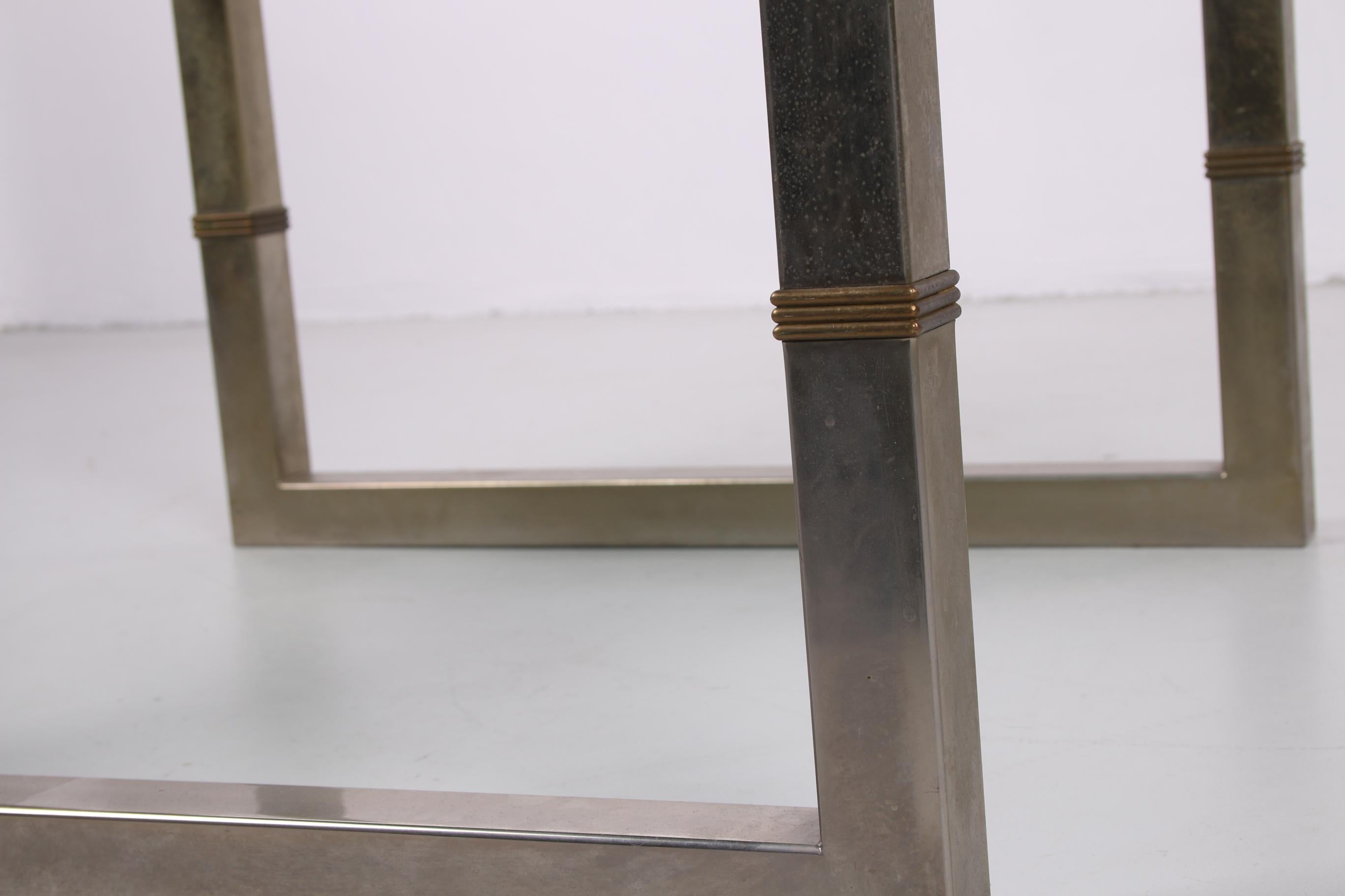 Cette magnifique table basse a été conçue par le designer hongrois Peter Ghyczy dans les années 1980.

La table se compose d'une plaque de verre de 30 mm d'épaisseur qui repose sur un cadre en acier inoxydable. Ce cadre est constitué d'un tube carré