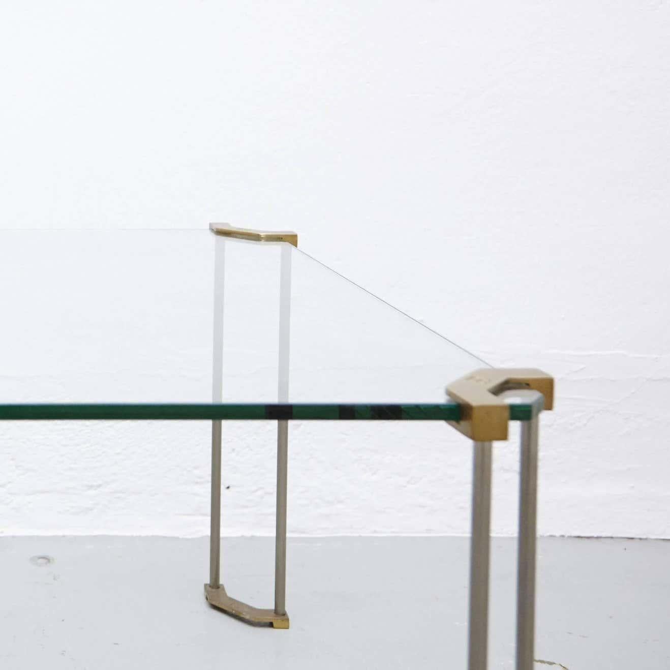 Der Tisch ist aus Glas und sandgegossenem Messing gefertigt. Die Beine werden von erfahrenen Handwerkern in den Niederlanden von Hand gegossen. Das Messing weist die typischen Merkmale des Gussverfahrens auf, und nur einige Teile sind poliert.

Nach