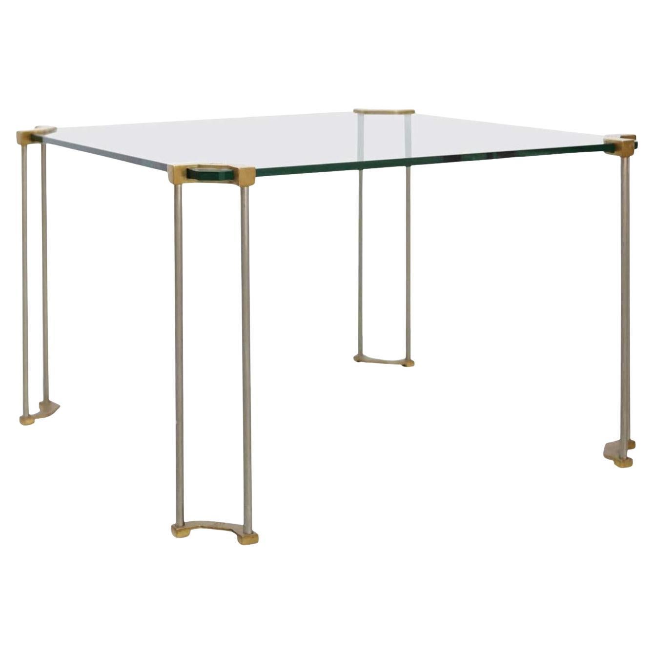 La table est fabriquée en verre et en laiton moulé au sable. Les pieds sont moulés à la main par des artisans très qualifiés aux Pays-Bas. Le laiton présente les caractéristiques typiques du processus de moulage et seules certaines parties sont