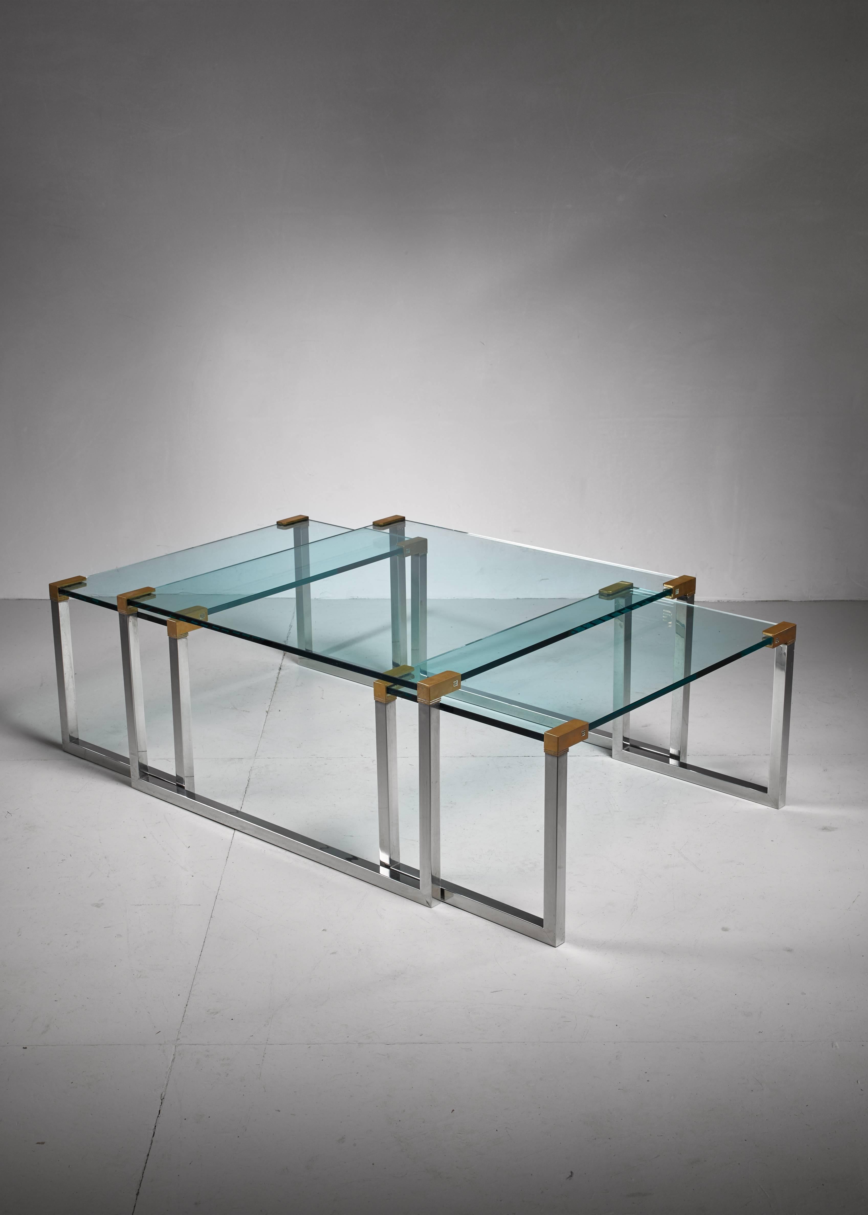 A set of three modular side or coffee tables by Dutch-Hungarian designer Peter Ghyczy. The tables are made of a chrome and brass frame with a glass top.

The measurements stated are of the large table. The two smaller tables are 45 by 83 cm and 42